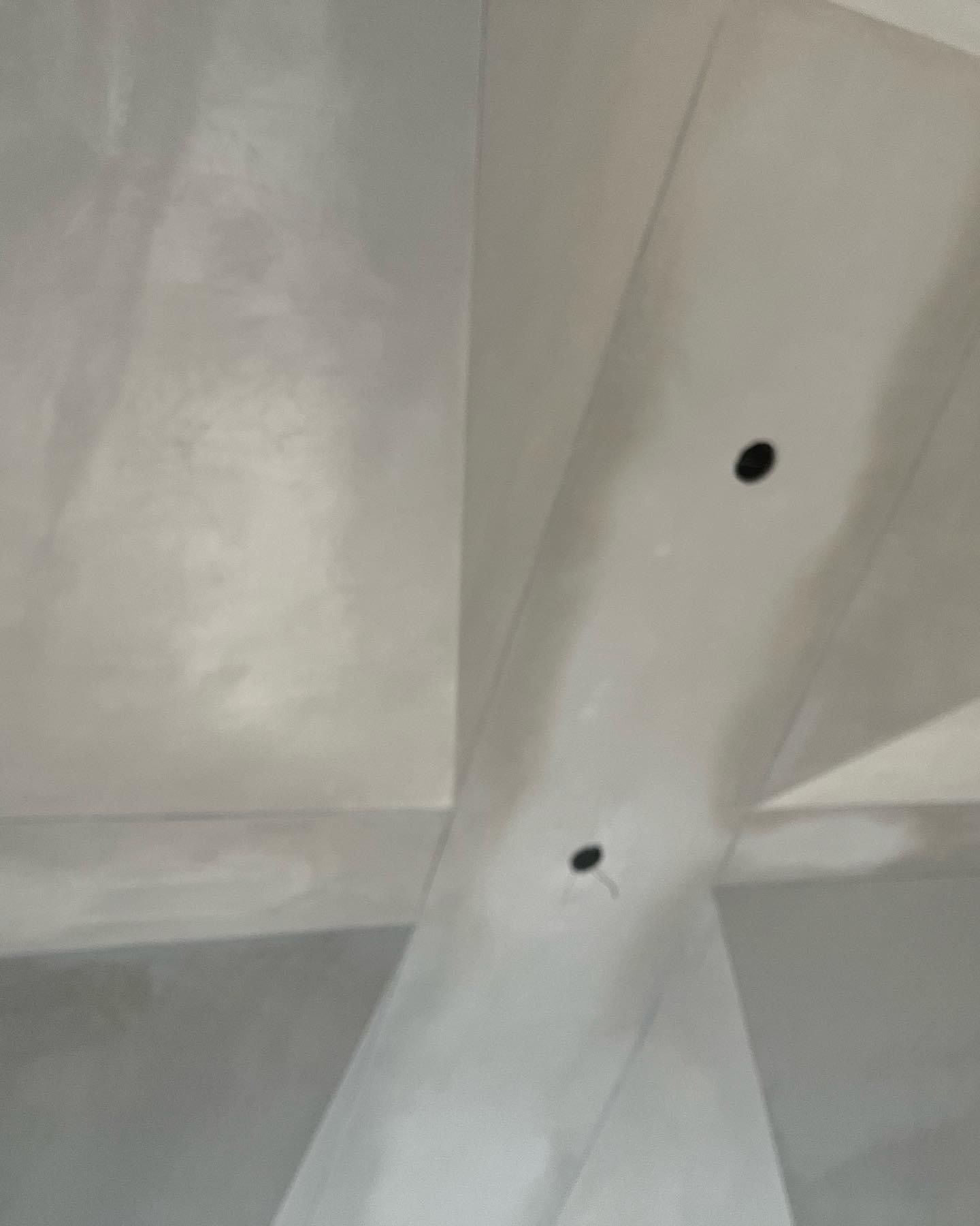 Close-up of a white ceiling beam with two small black holes