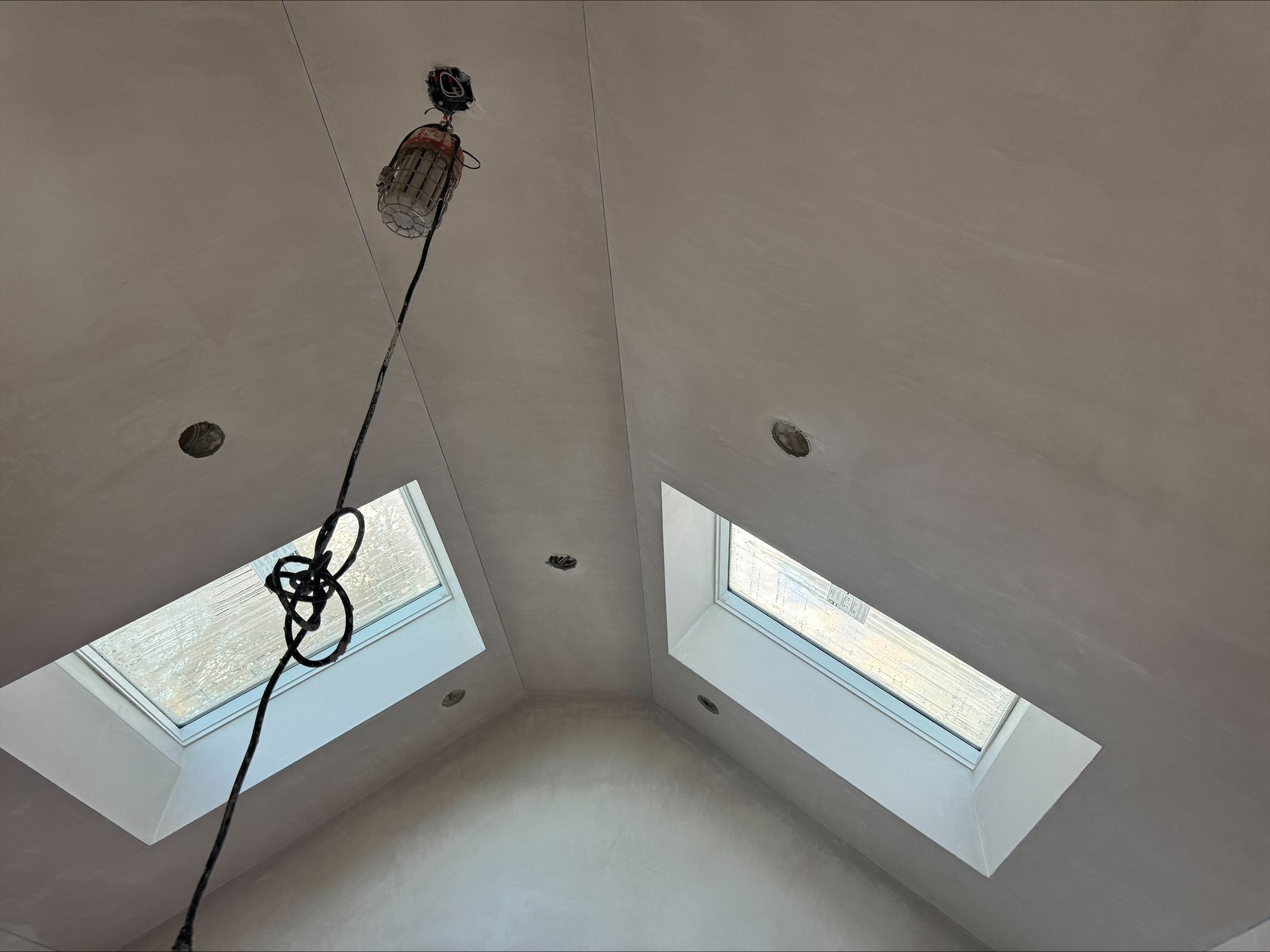 Ceiling view with two skylights and a hanging light fixture on a white vaulted ceiling