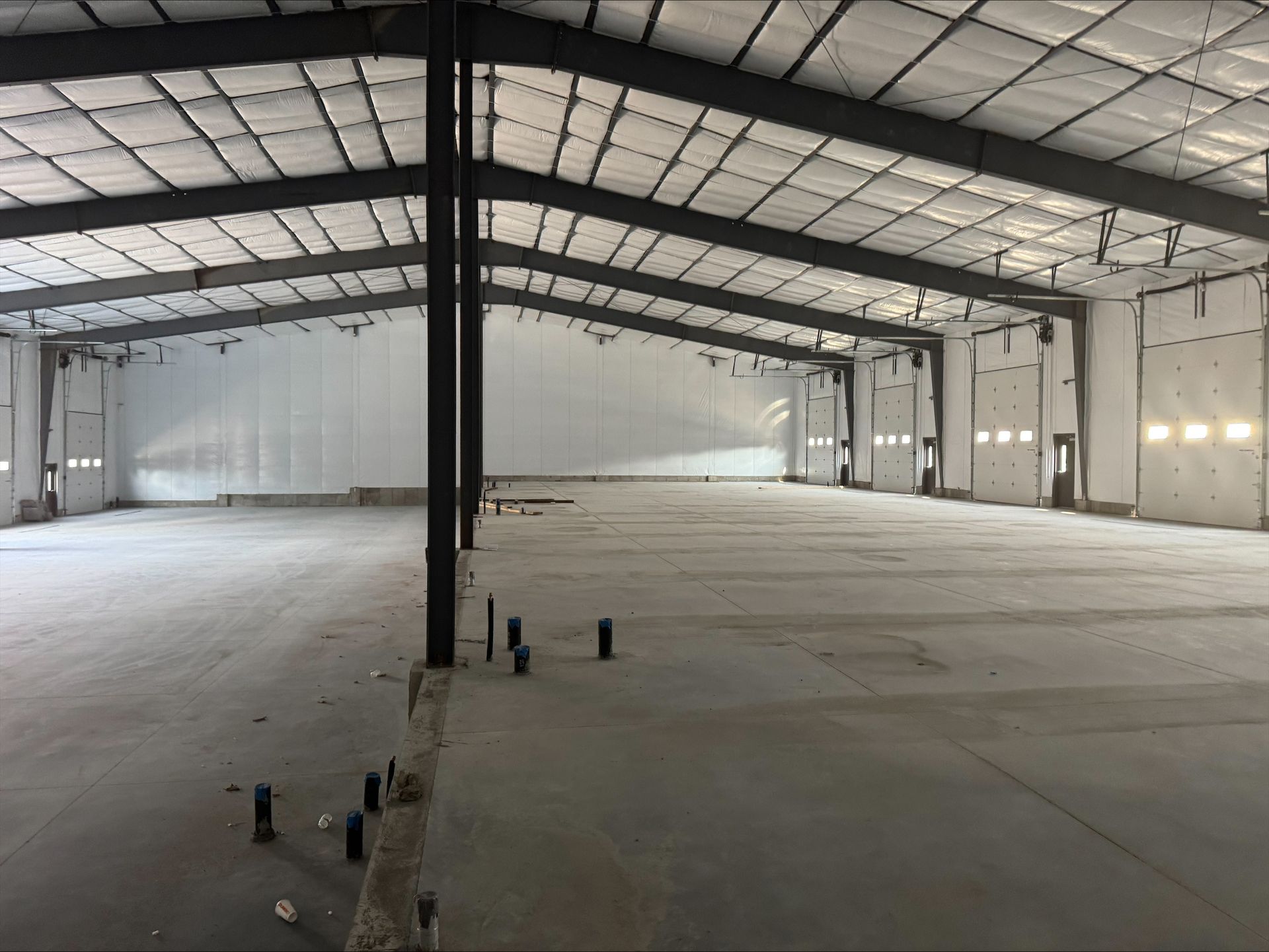 Empty industrial warehouse interior with concrete floor and metal roof supports