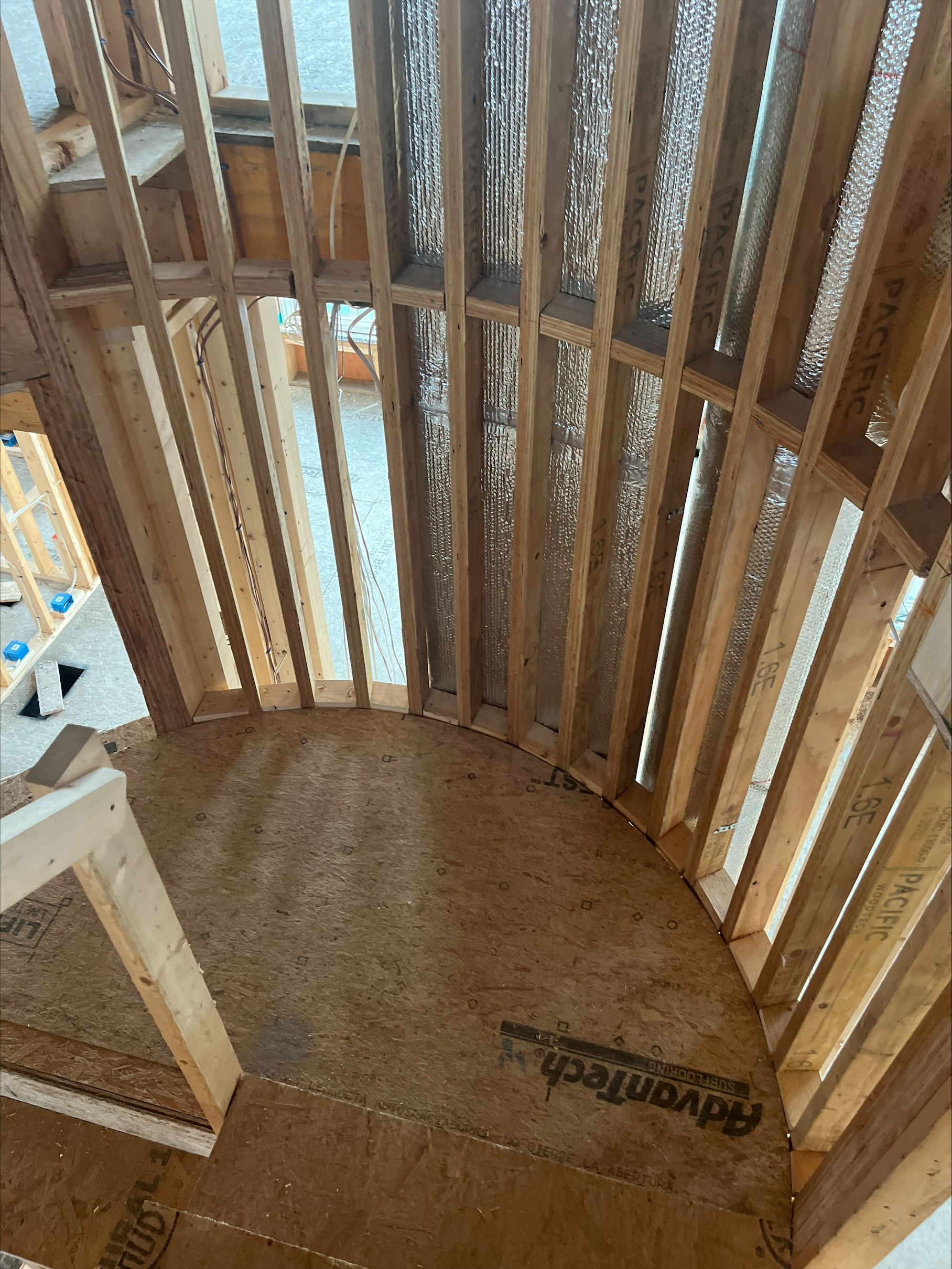 Curved wooden stairwell with vertical slats, showing a view down to a lower floor through the railing.