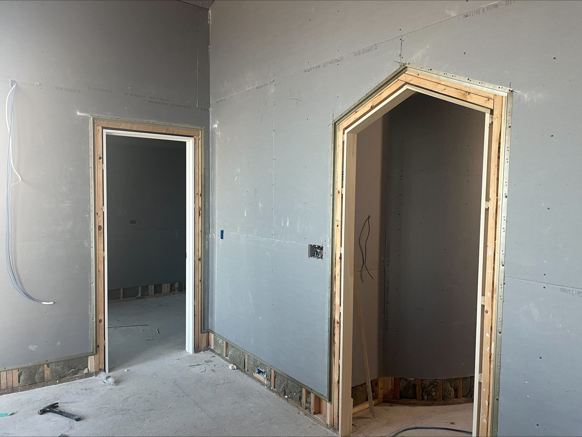 Unfinished interior with drywall, two doorways, and exposed baseboards during renovation