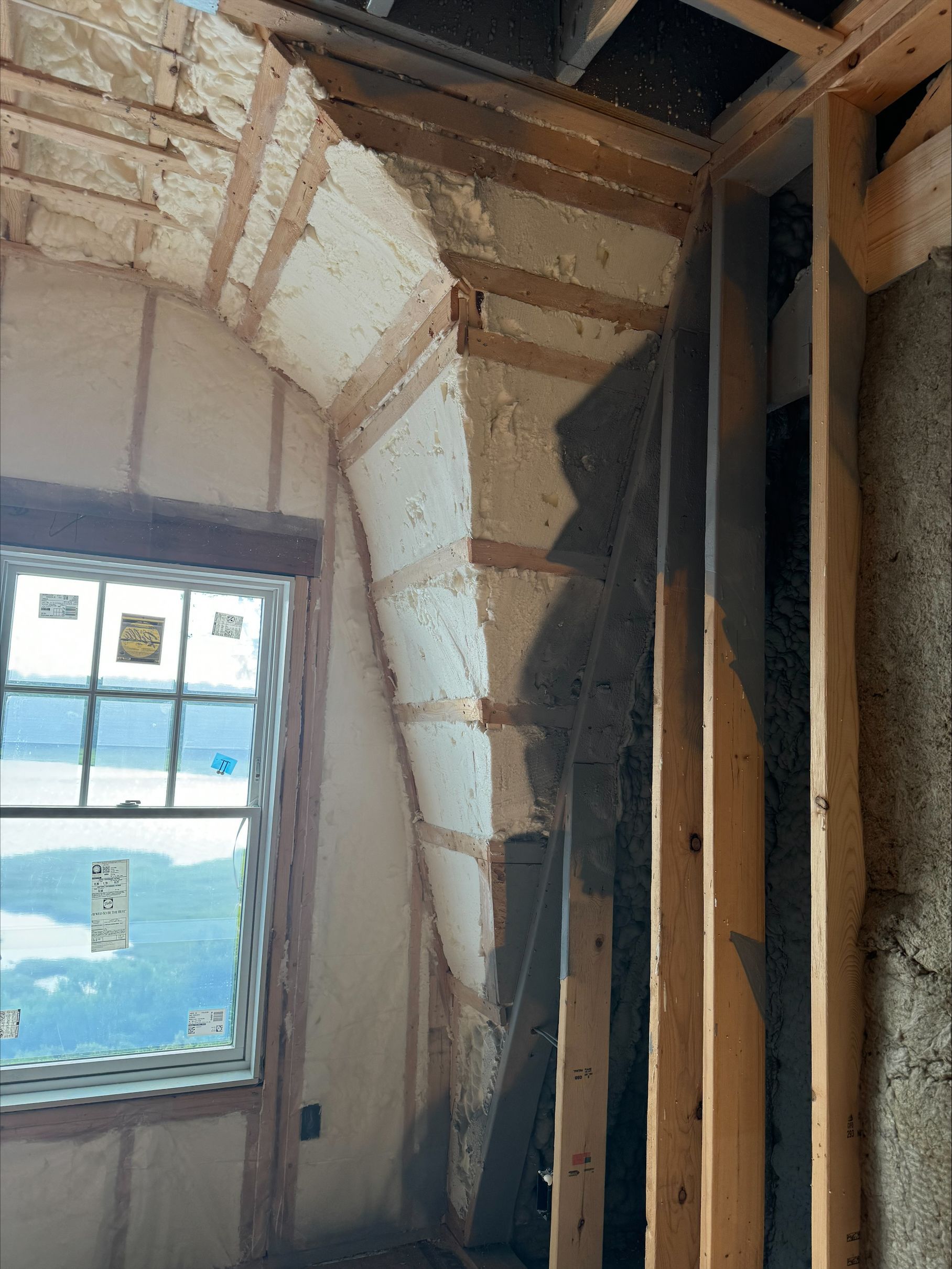 Unfinished room with exposed insulation, wood framing, and a window overlooking water