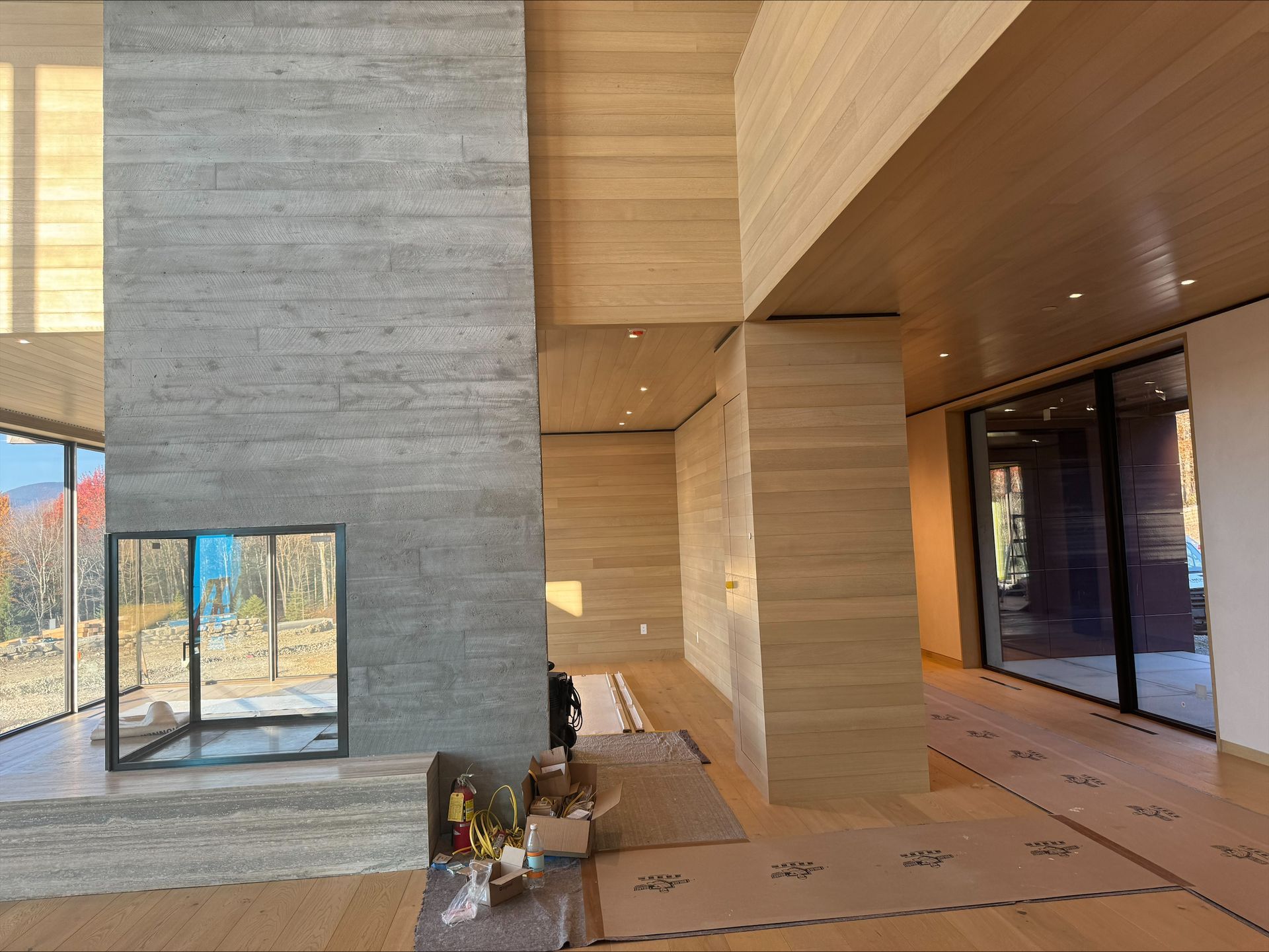 Modern building interior with concrete walls, wood ceiling, glass doors, and large windows facing outside
