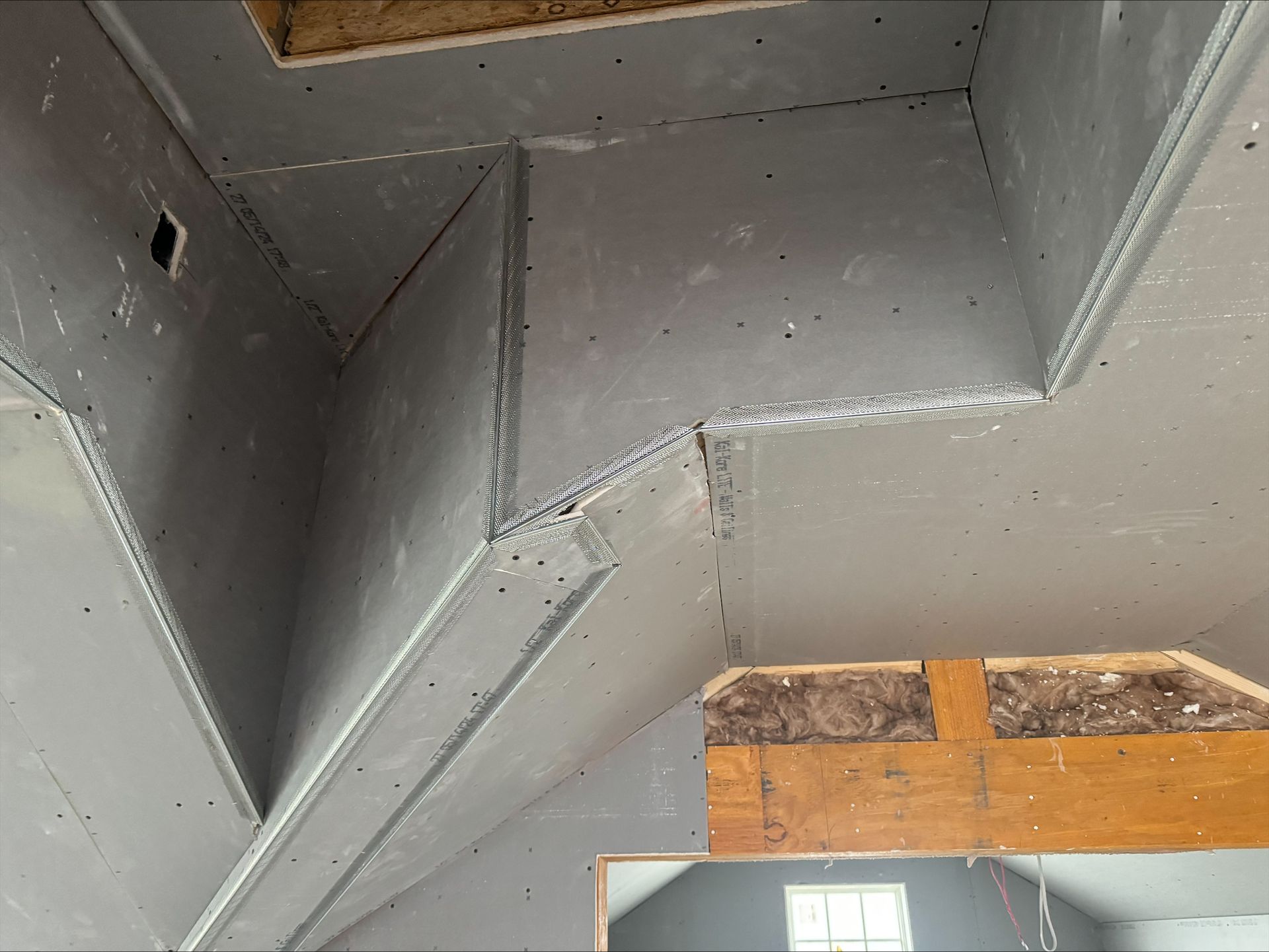 Gray metal ductwork with angled seams and a visible orange wooden structure in the background