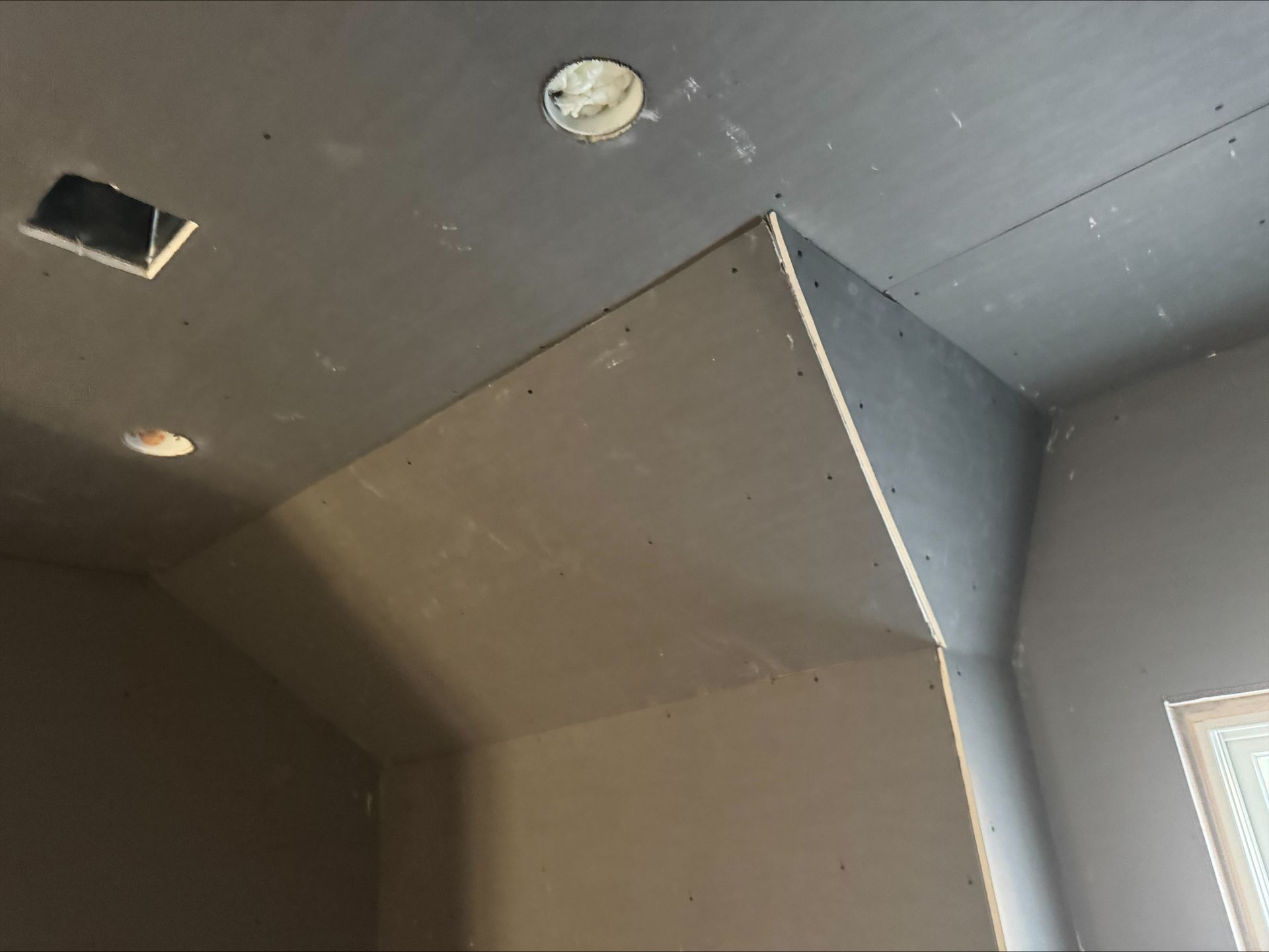 Ceiling corner with dark gray panels, a white column, recessed light, and a vent opening