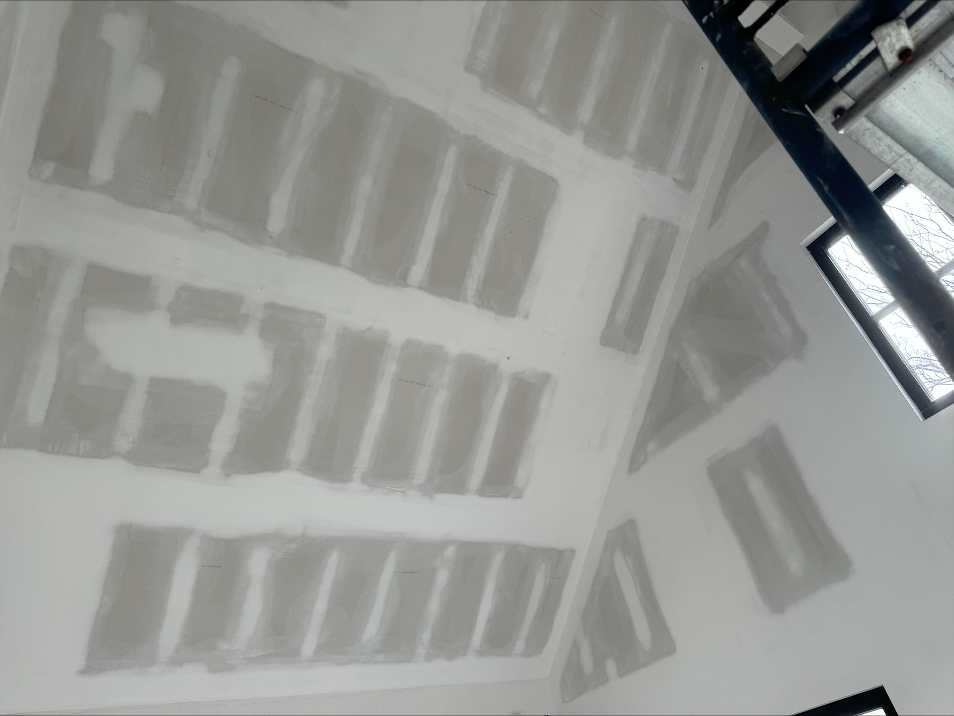 Interior room with unfinished drywall and taped seams, viewed upward toward a stairwell opening.