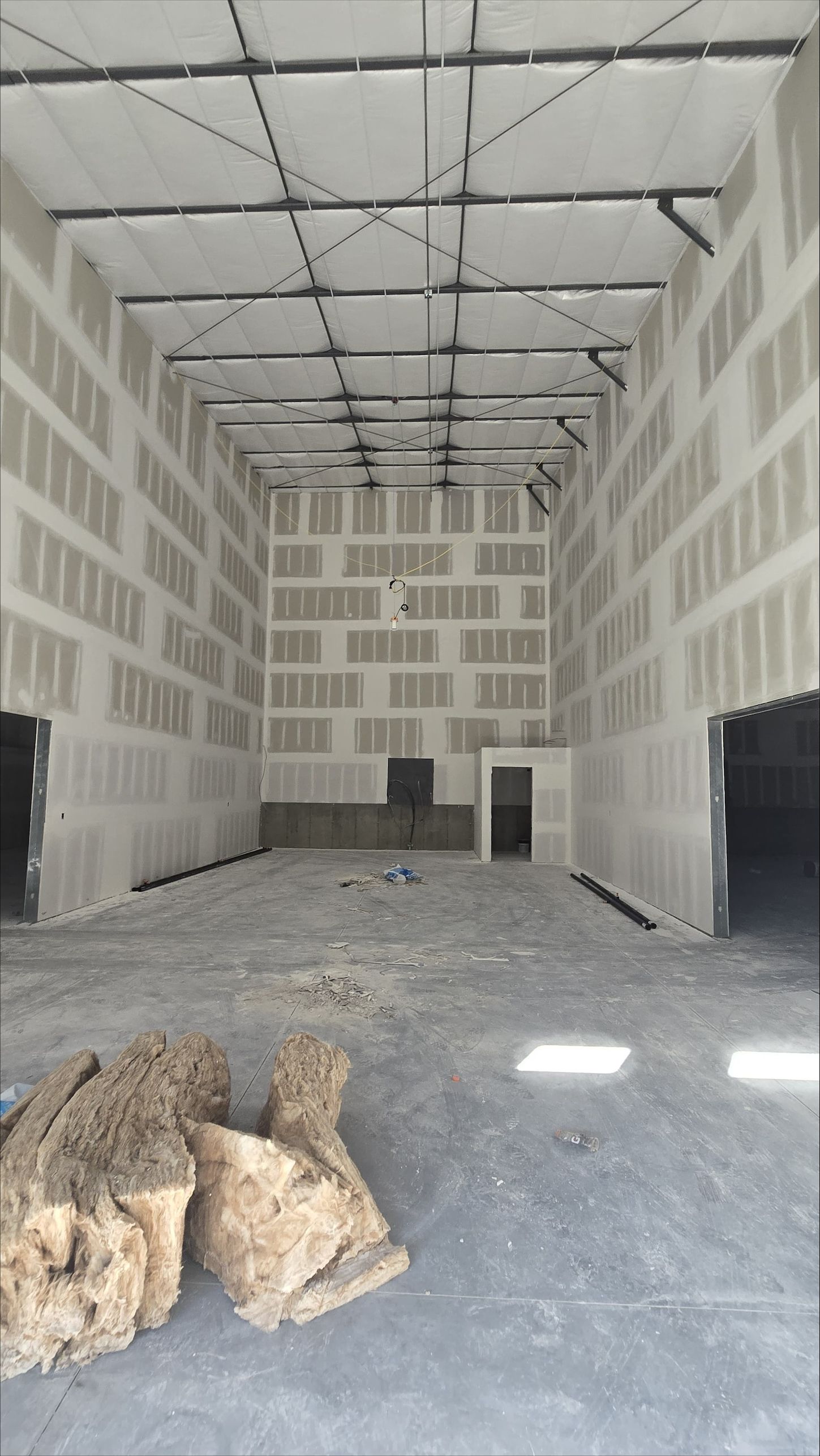 Empty unfinished warehouse interior with concrete floor, block walls, and construction debris.