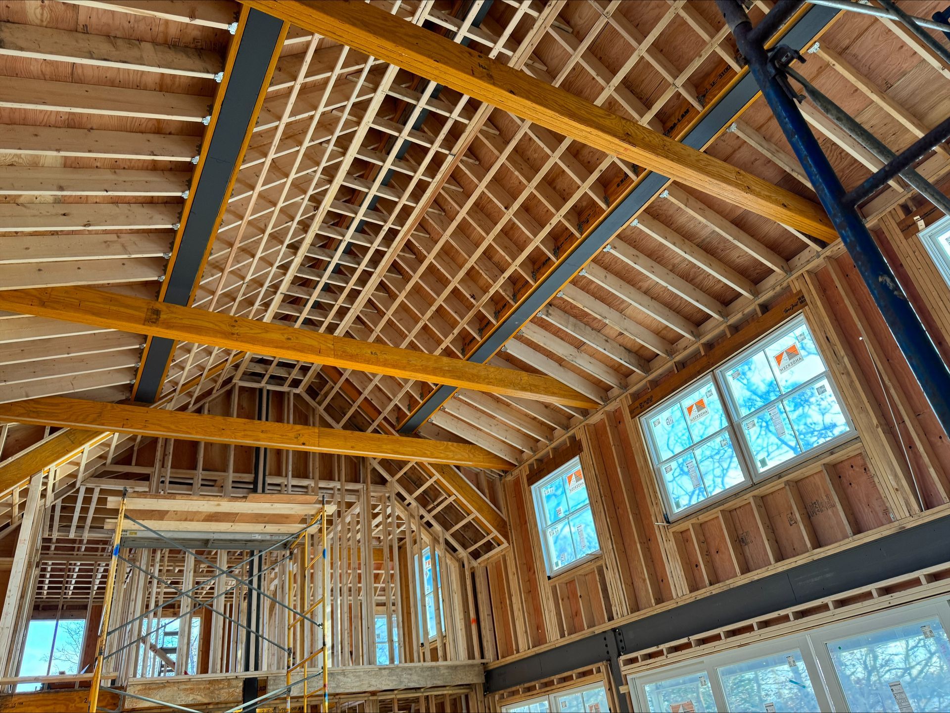 Interior of a wooden building under construction, with exposed beams and framed windows letting in daylight