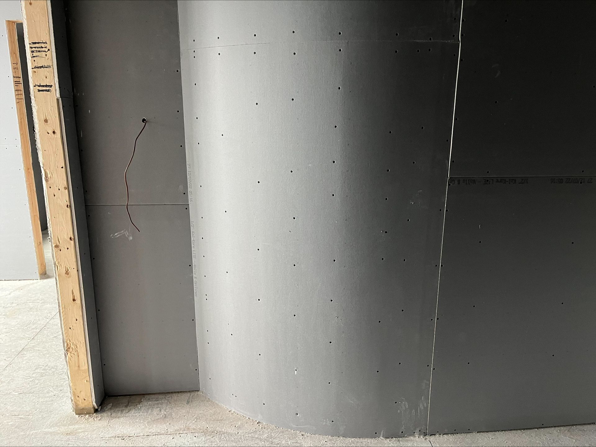 Partially built wall with gray drywall and exposed wooden framing at left