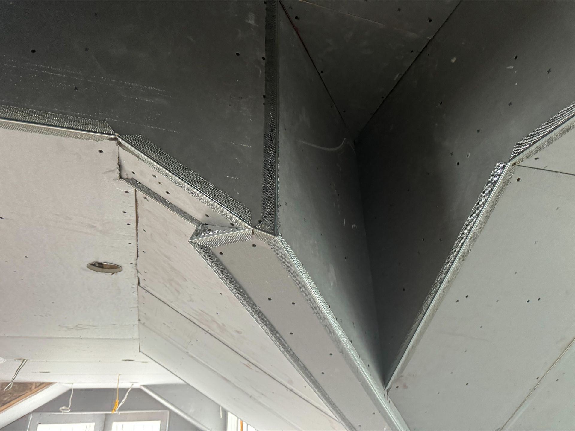 Close-up of a metal aircraft wing junction with rivets and seams, showing a dark central gap.