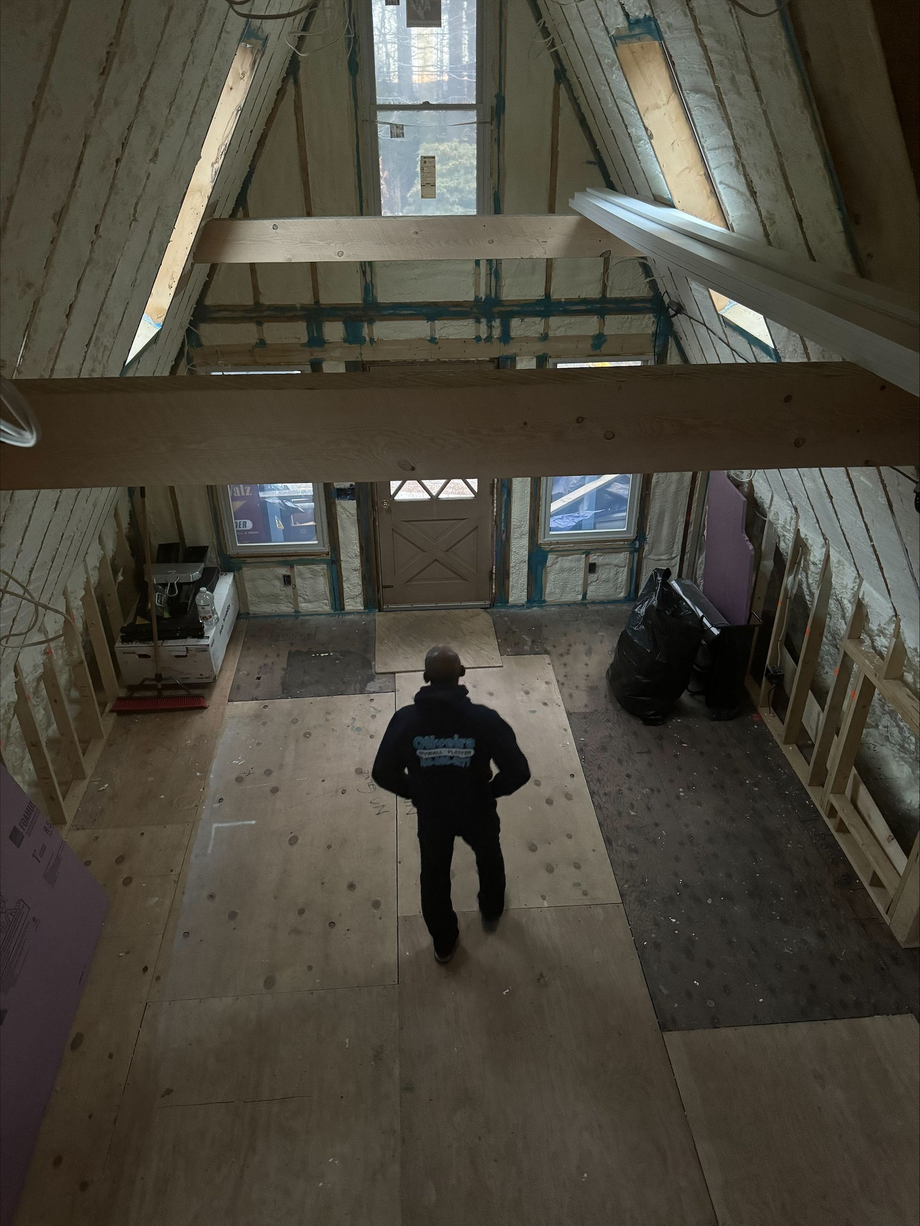 Person walking inside a modern A-frame cabin with large windows and exposed wood beams.