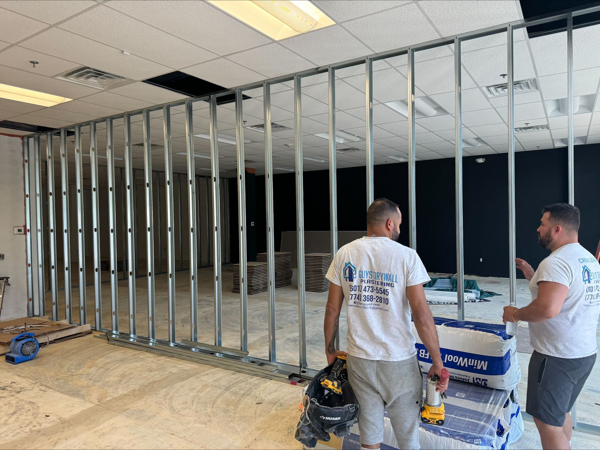 Workers framing an interior wall with metal studs in an unfinished room