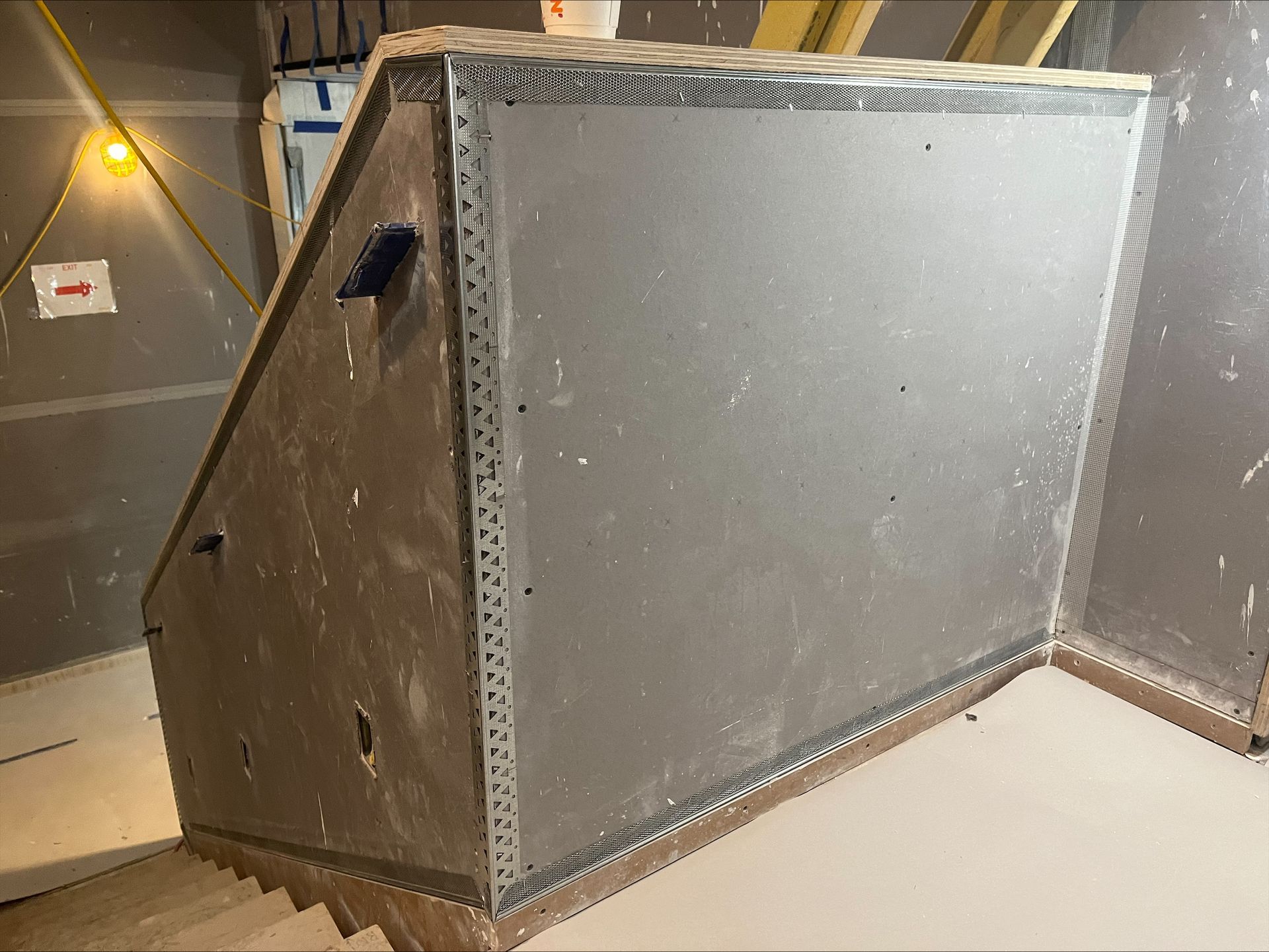 Large gray insulated box or ducting unit in an indoor utility room, with a small black handle on the side