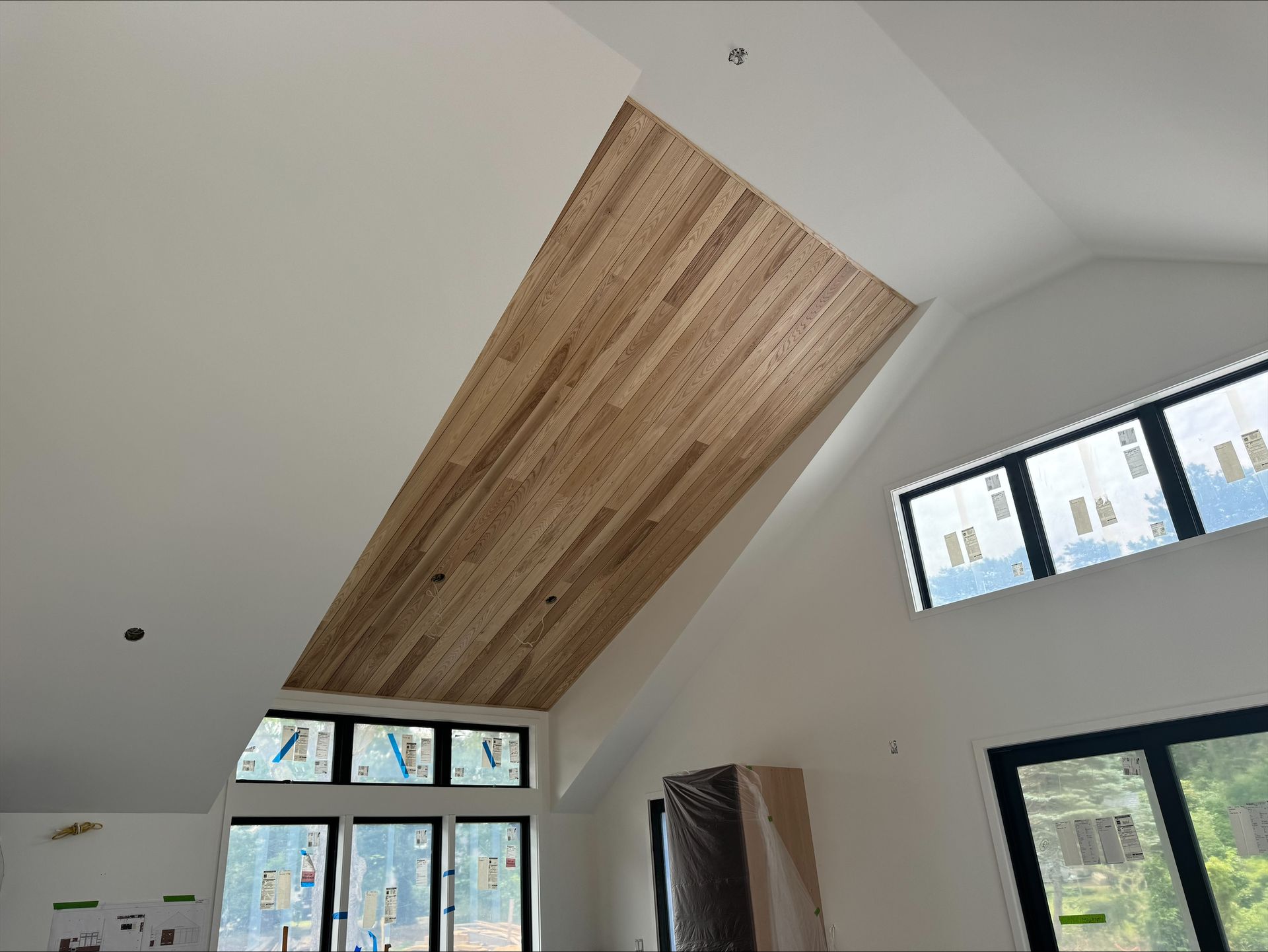 Interior with a slanted wood-plank ceiling and large windows in a bright room