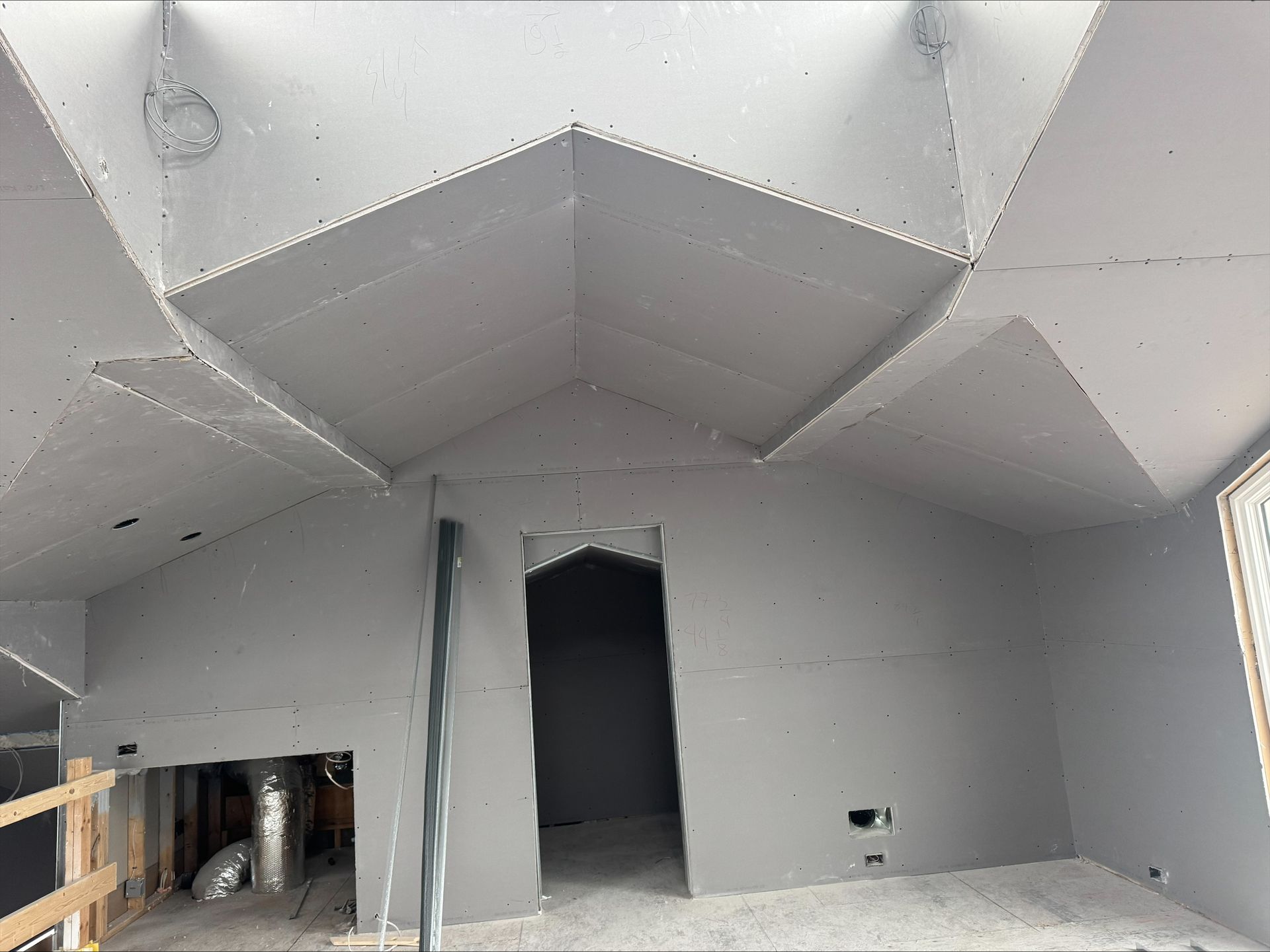 Unfinished room with gray walls, exposed ceiling, and open doorways under construction