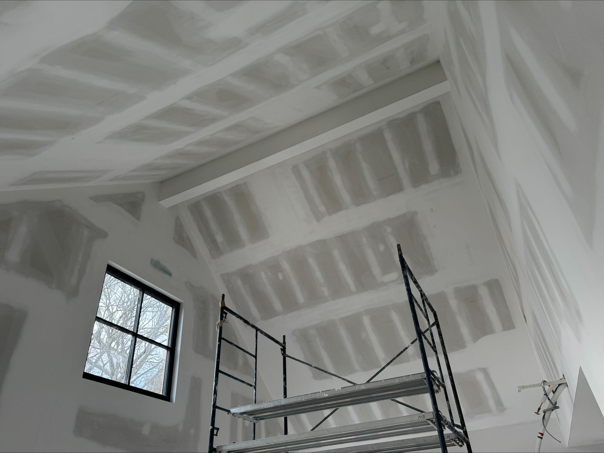 Interior under renovation with exposed framing, scaffold, and a small window letting in light