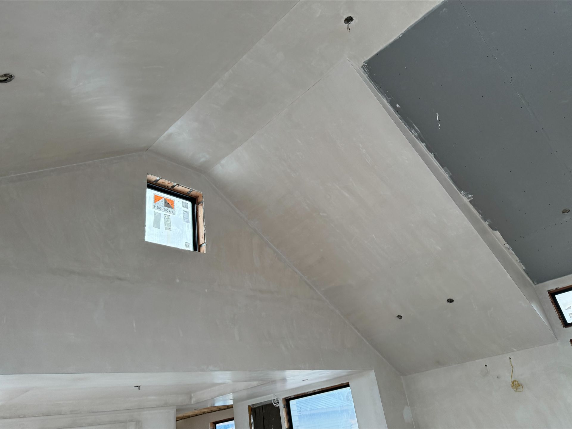 Unfinished interior ceiling with gray drywall panels and small window openings.
