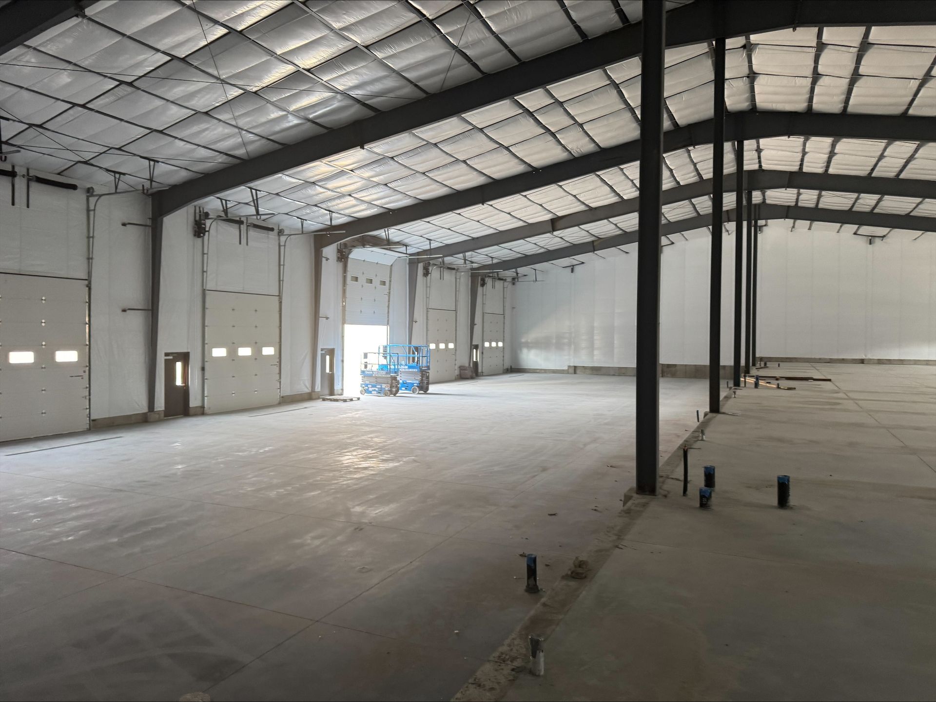 Empty warehouse interior with metal roof, concrete floor, and support columns