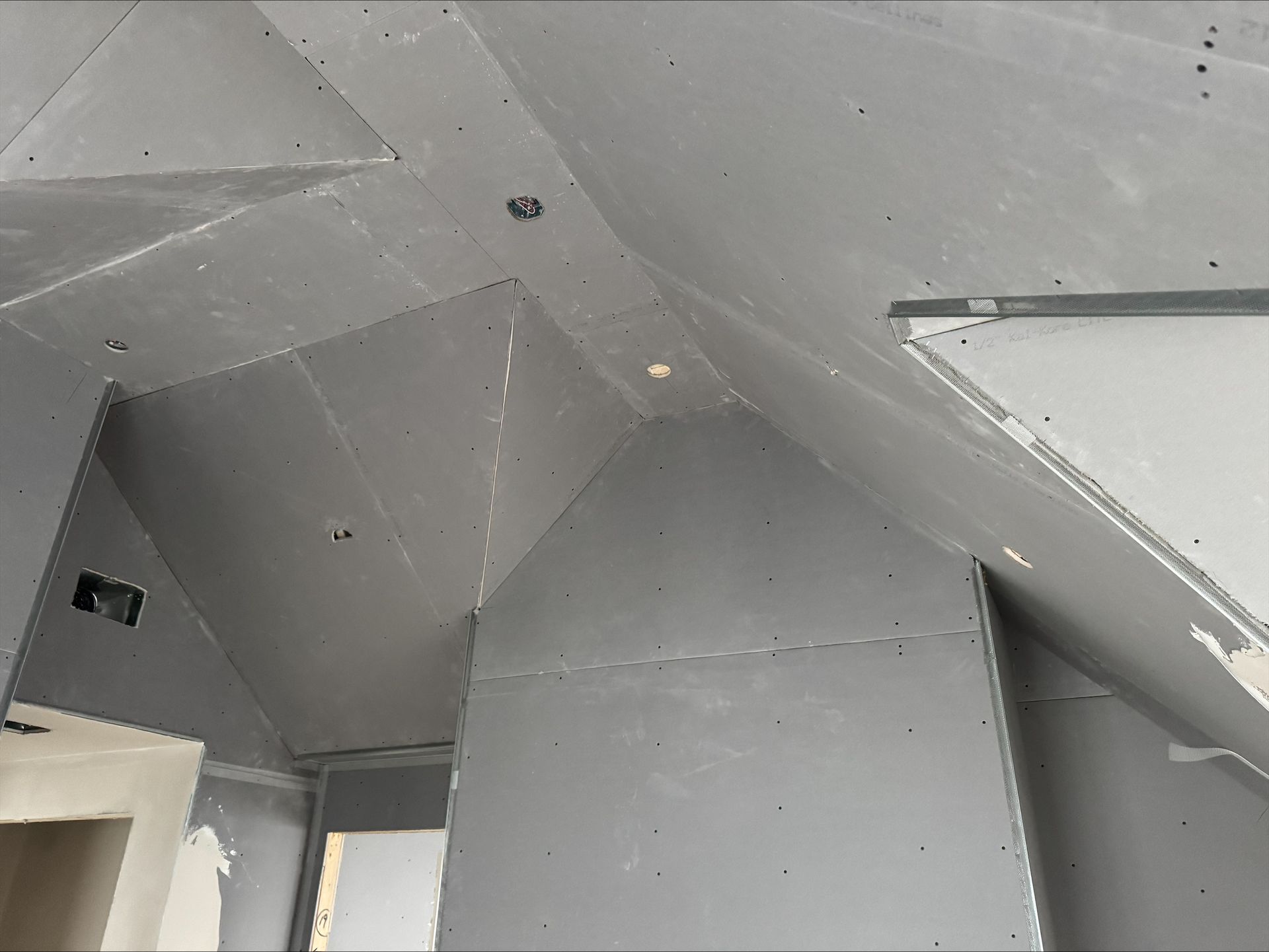 Gray geometric ceiling with angled panels and a small light fixture near the corner