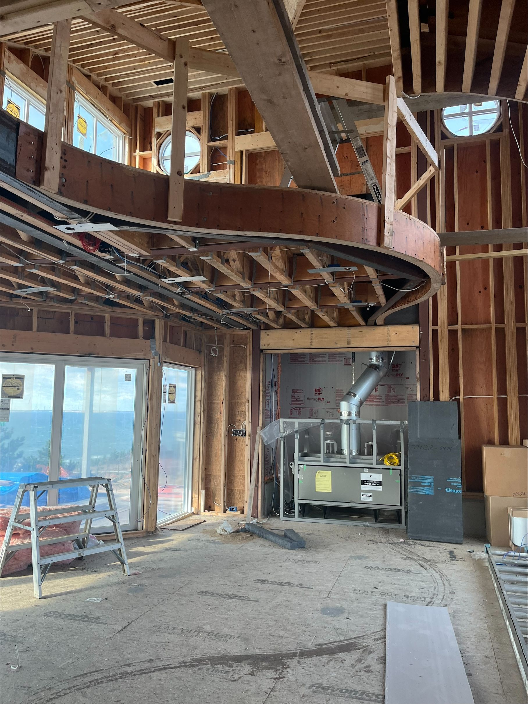 Interior of a gutted room under construction, with exposed framing, staircase, and a generator by the wall.
