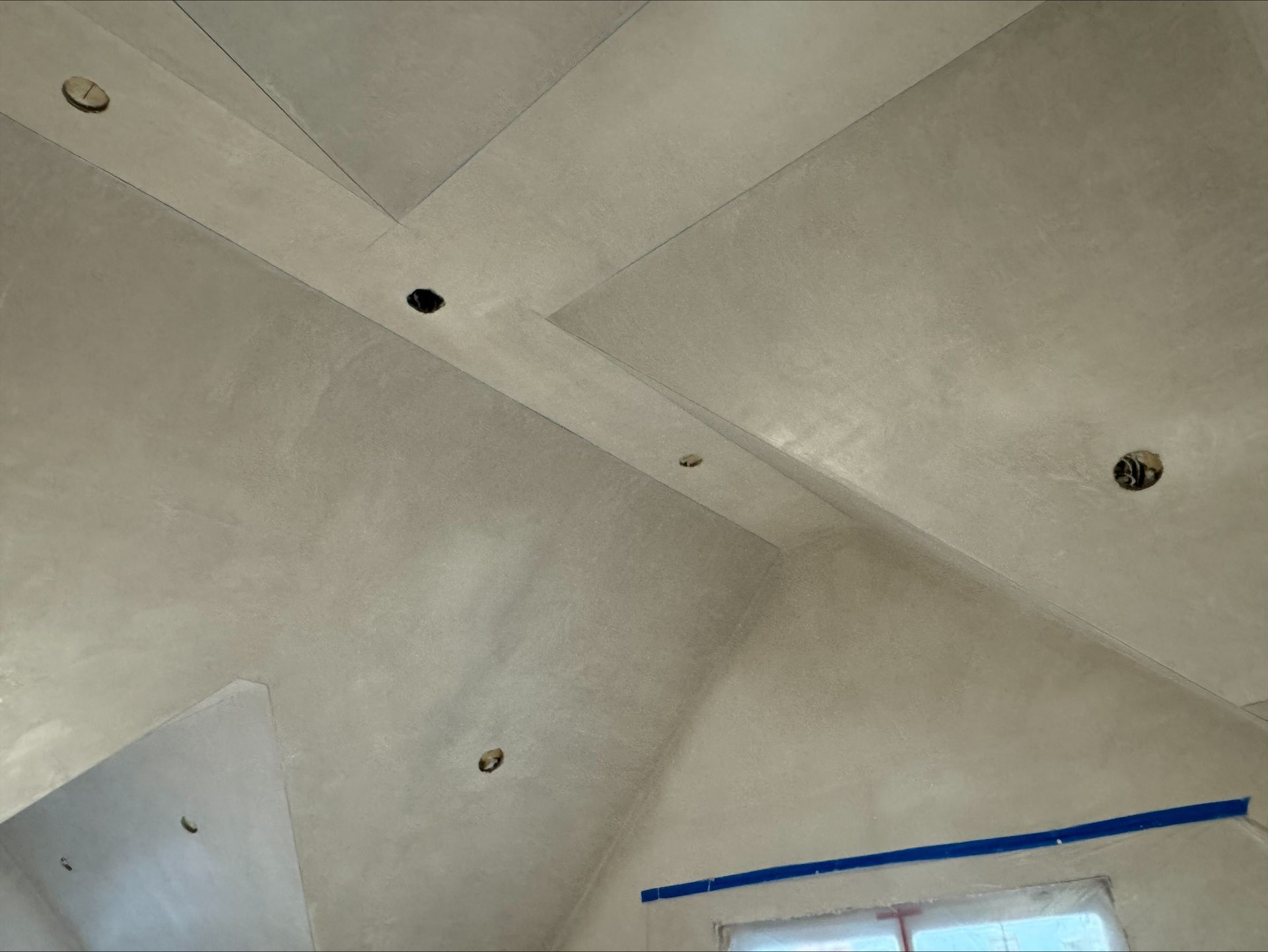 Ceiling with white panels, recessed lights, and a strip of blue painter’s tape along one edge