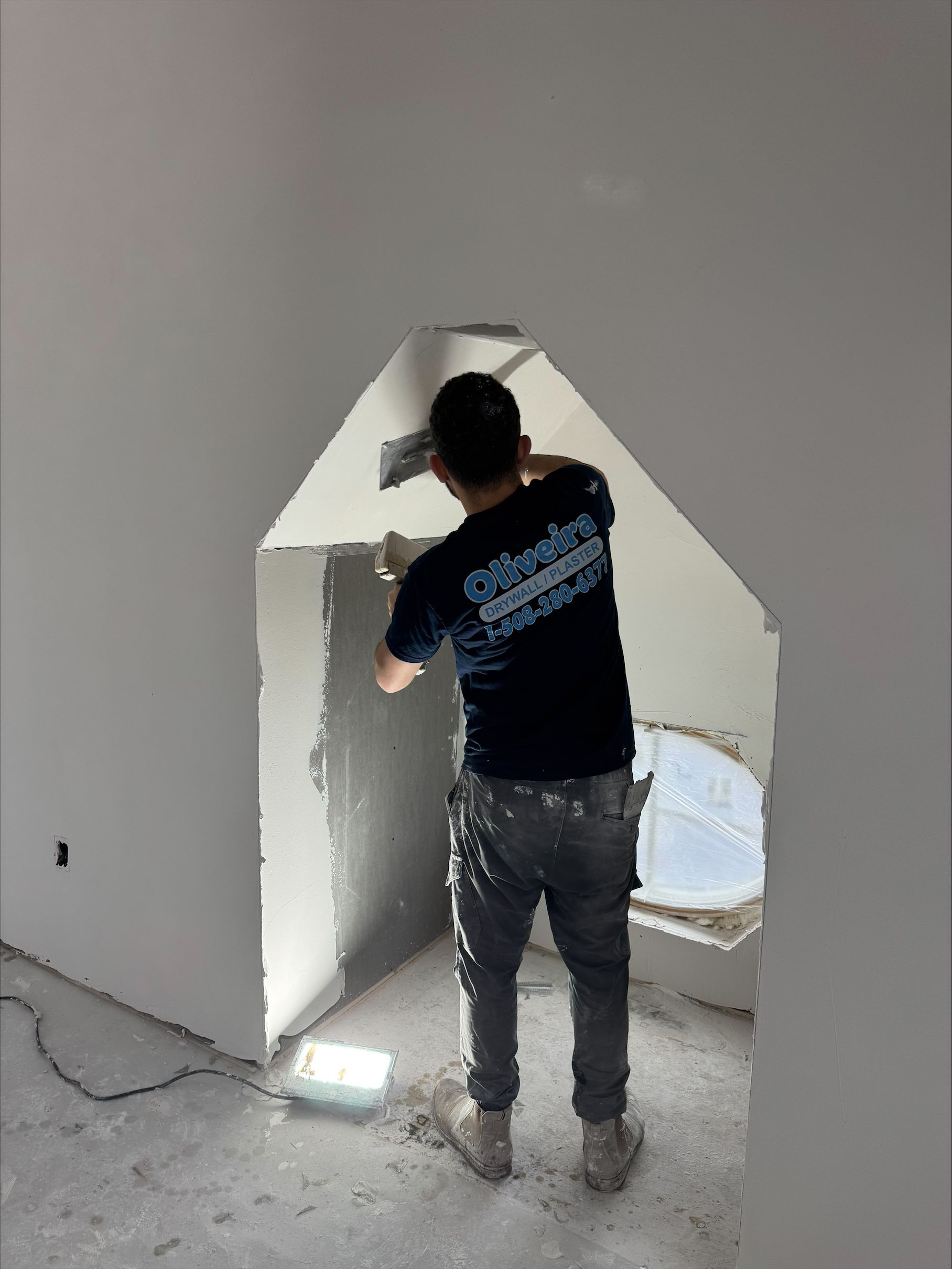 Worker plastering a wall opening inside an unfinished room
