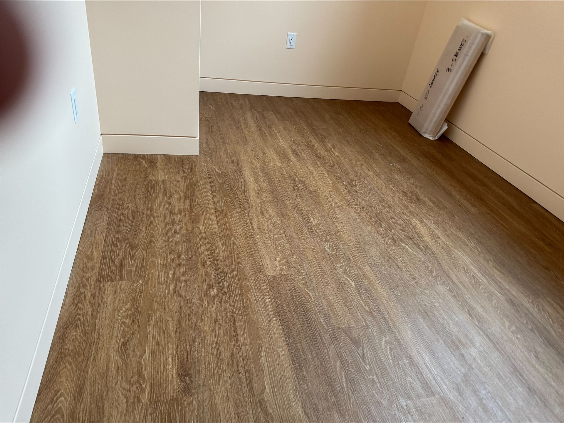 Empty room with wood-look flooring, white walls, and a radiator leaning against the right wall.