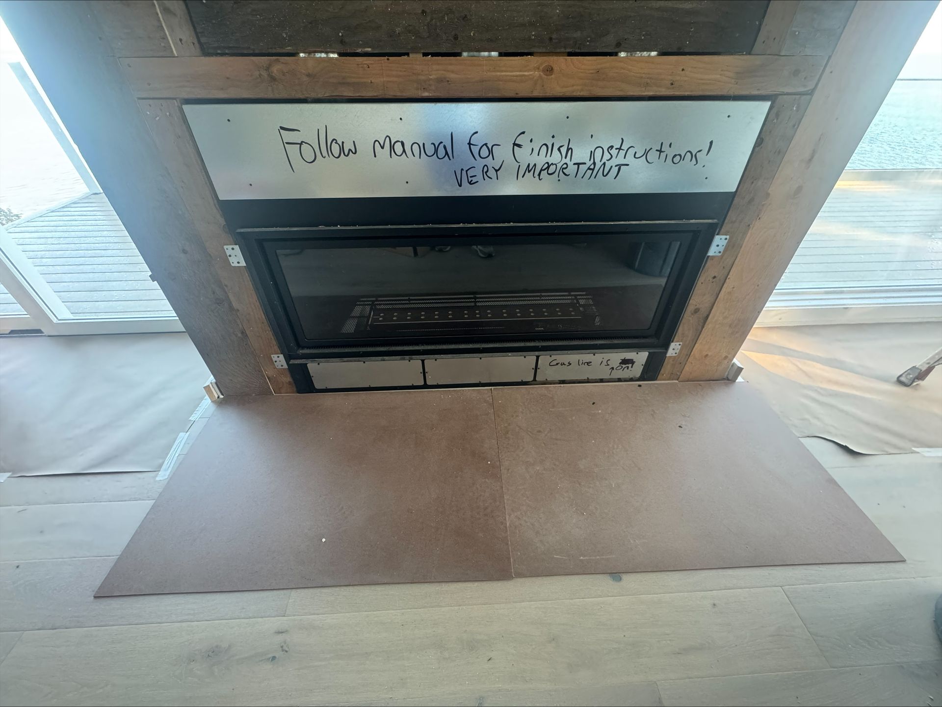 Fireplace with a handwritten “follow roads” sign above it and a protective floor mat in front
