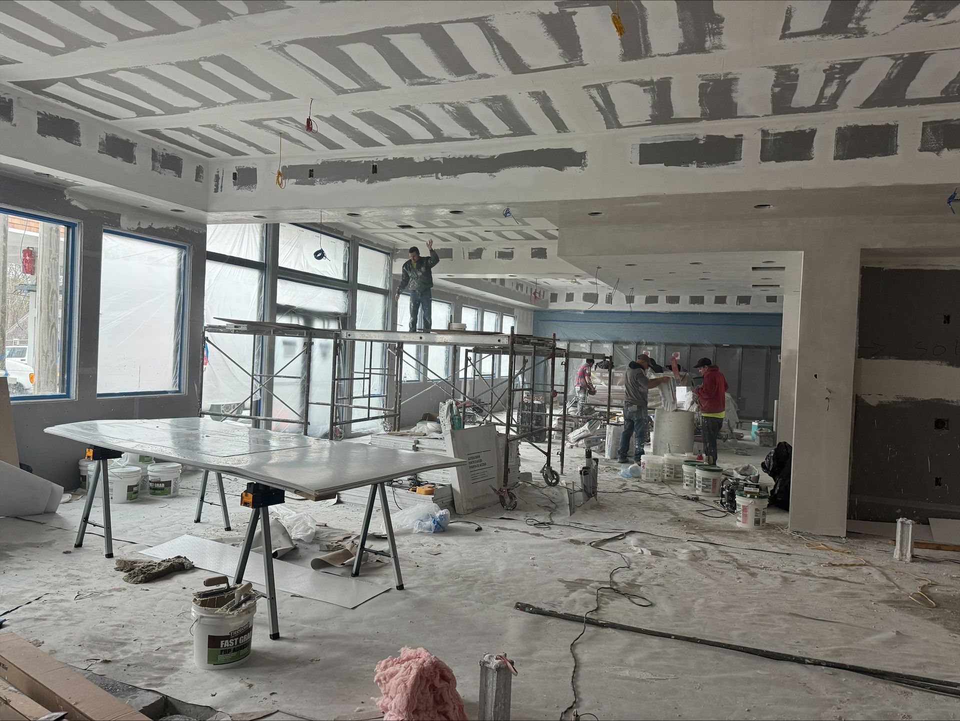 Dusty unfinished interior with scaffolding, construction tools, and workers during renovation
