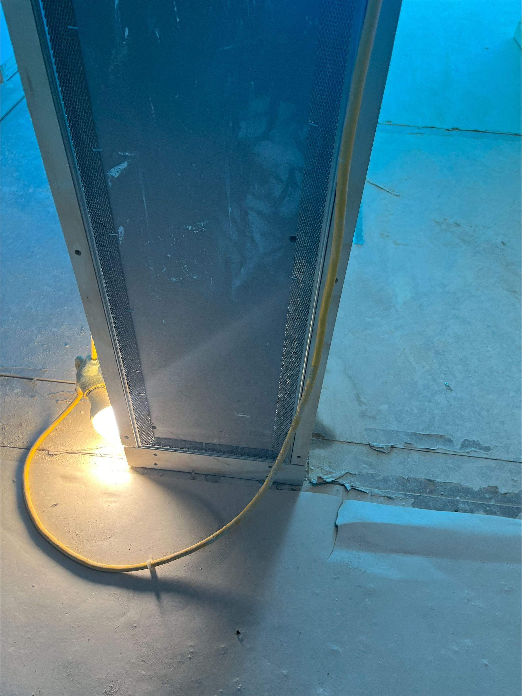 Steel beam beside a lit floor lamp and coiled cable in a blue-lit construction site