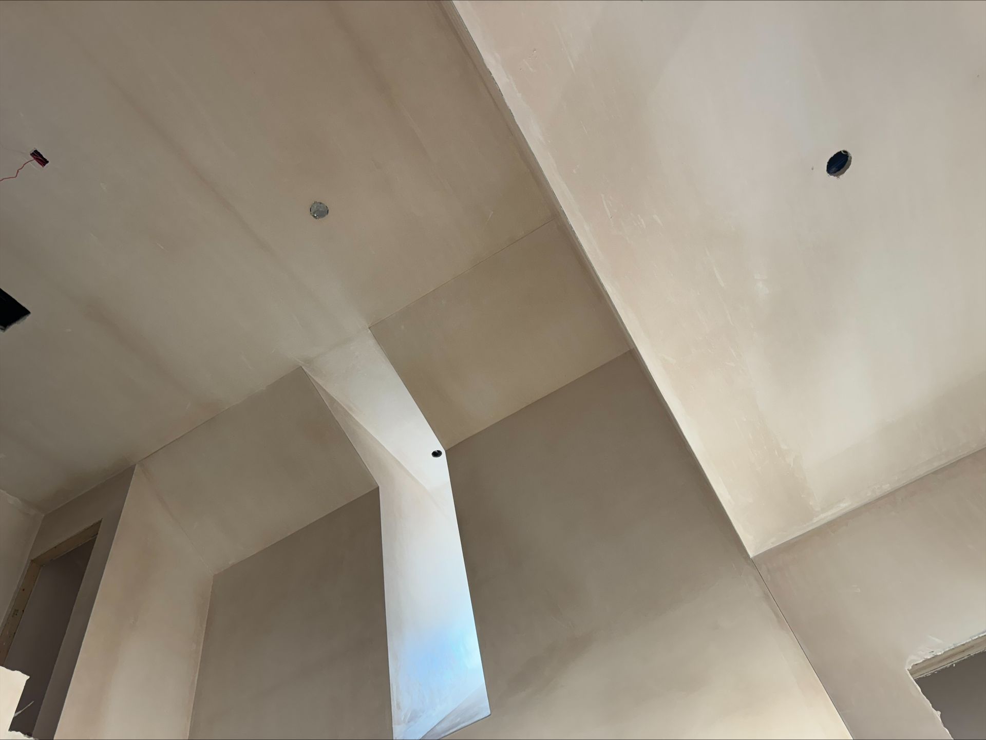 Interior view of a white ceiling with exposed beams and a skylight opening