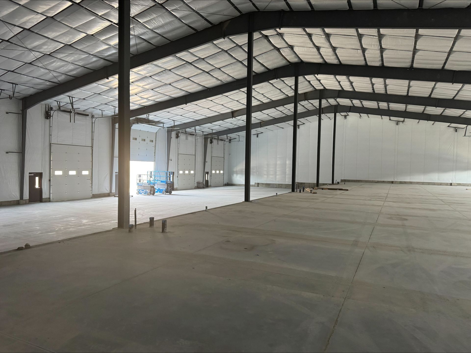 Empty warehouse interior with metal roof supports and a concrete floor