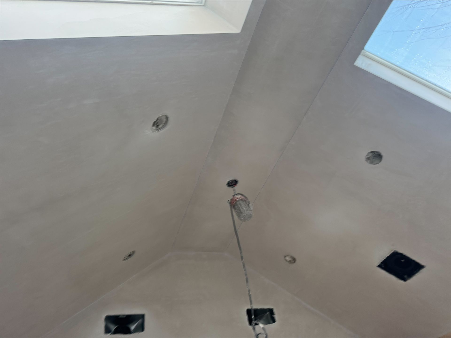 Ceiling with recessed lights, skylights, and hanging wires during construction