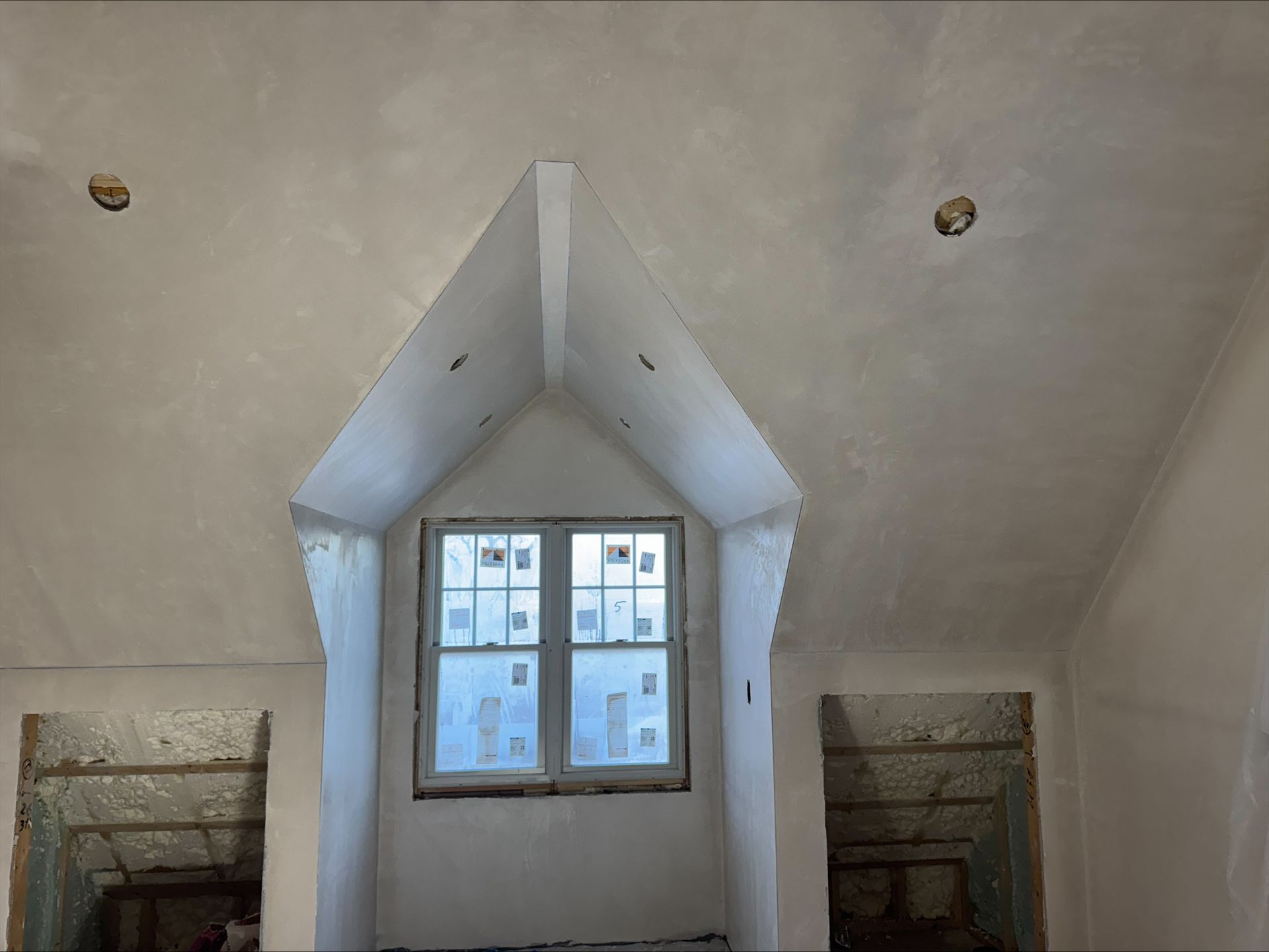 Renovation interior with a central dormer window and unfinished drywall walls