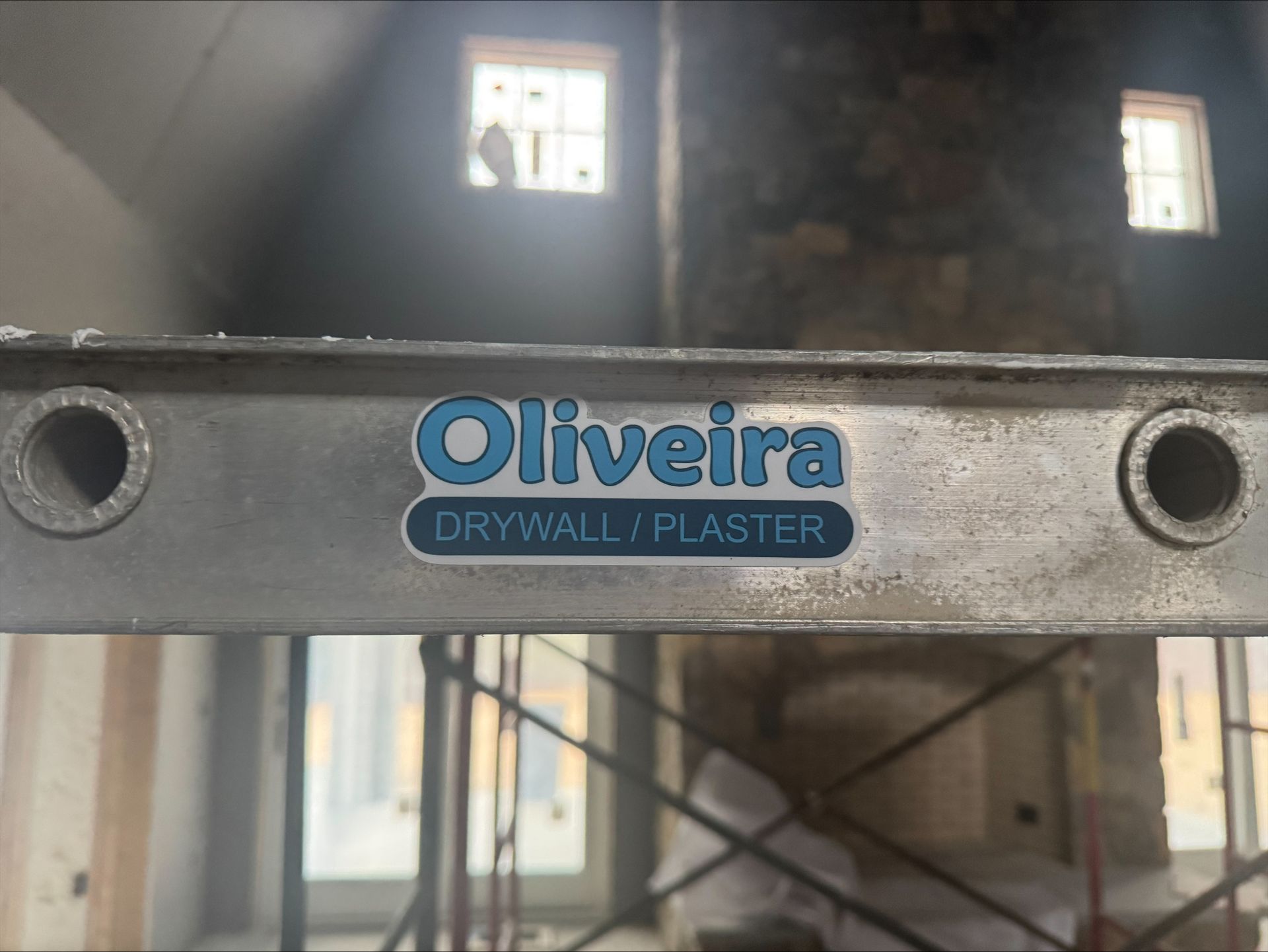 Construction site facade with Oliveira Drywall Plaster sign over an unfinished entryway