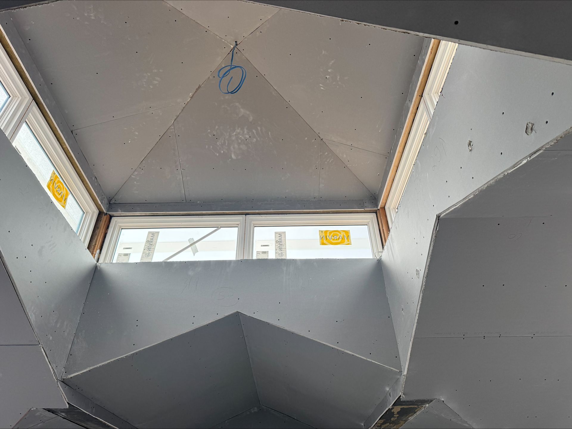 Geometric gray interior with slanted panels and a small window, viewed from below