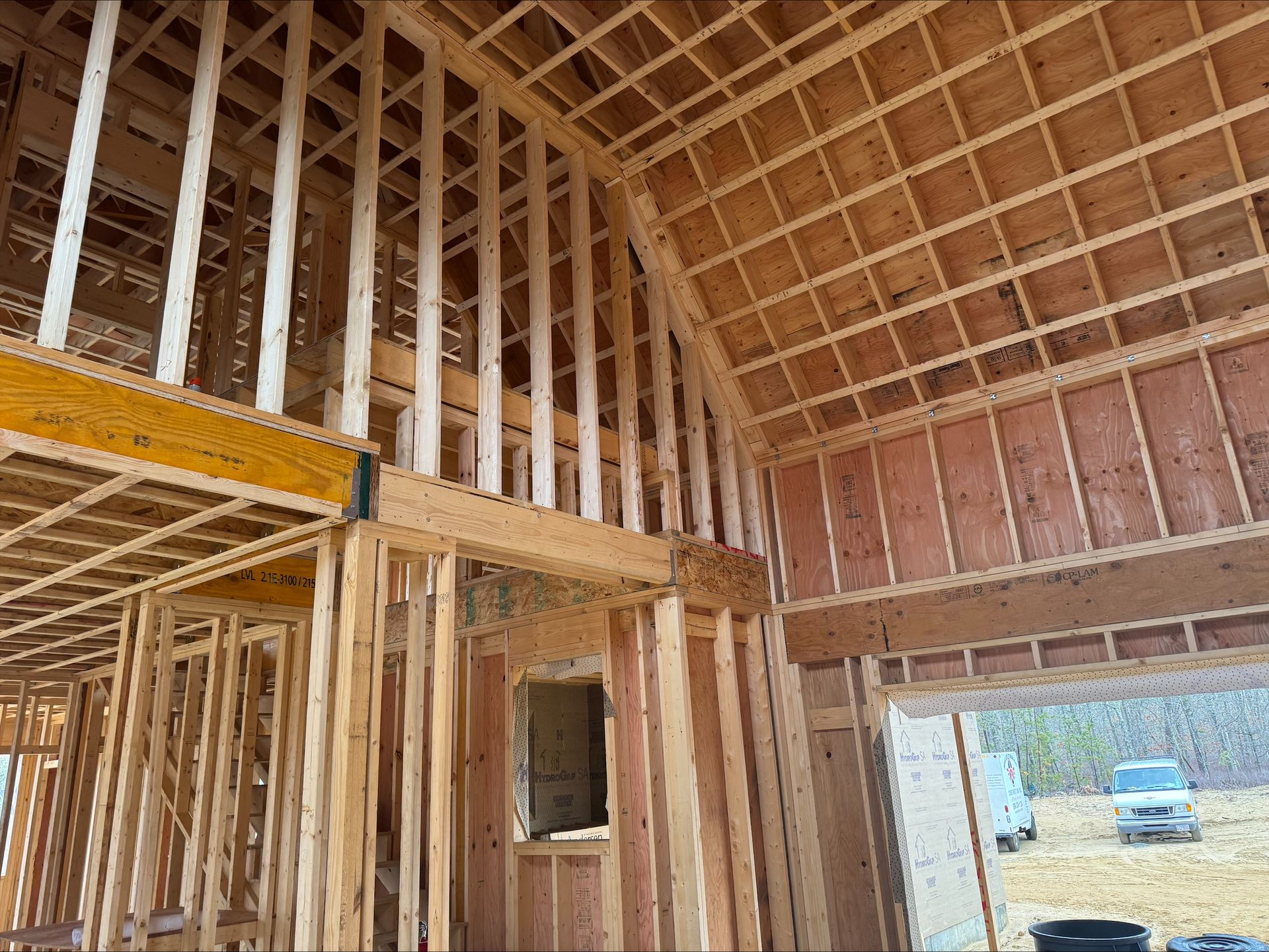 Wood-framed house under construction with exposed beams and a window opening.