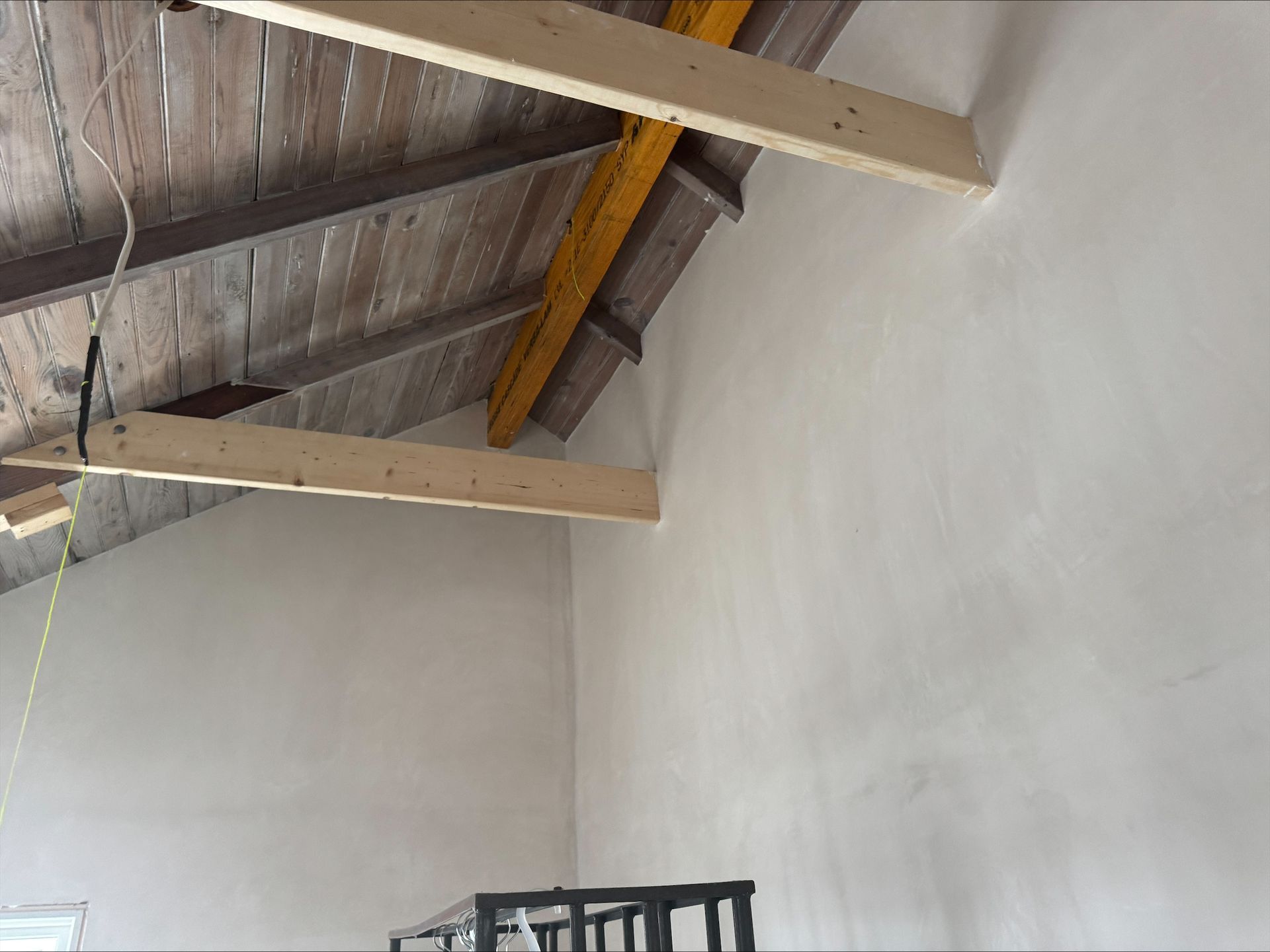 Interior view of a room with white walls and exposed wooden beams on a slanted ceiling