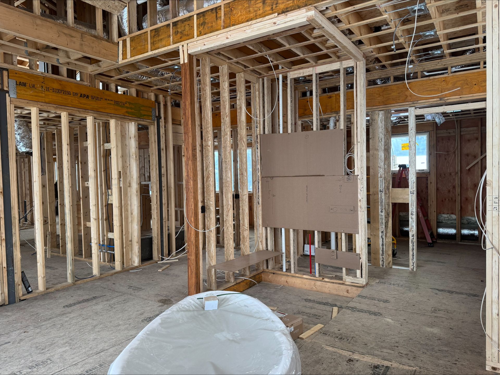 Framed interior of a house under construction with exposed walls, wiring, and a utility panel.