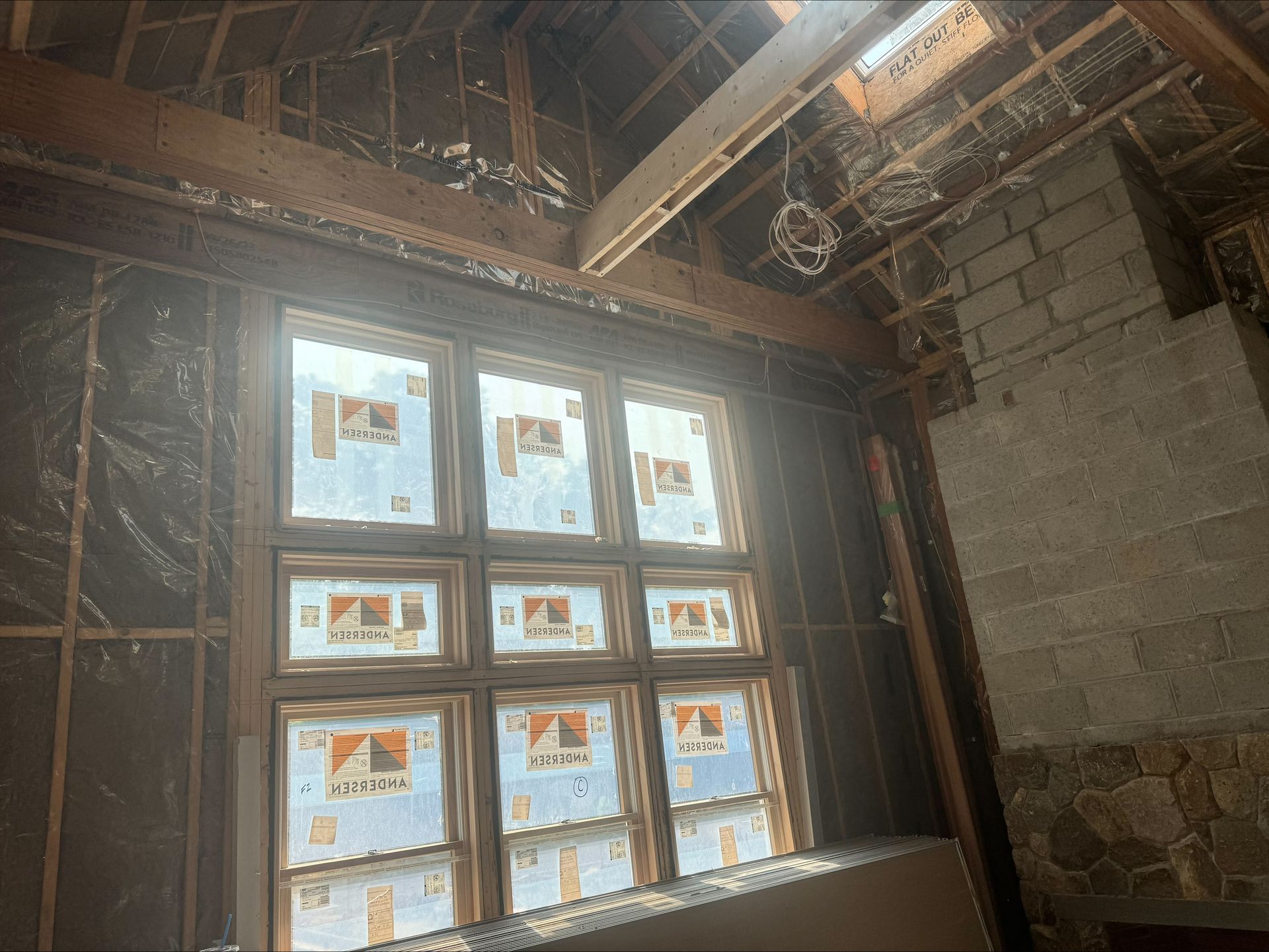 Dim unfinished interior with a large 8-pane window and exposed wood framing overhead.