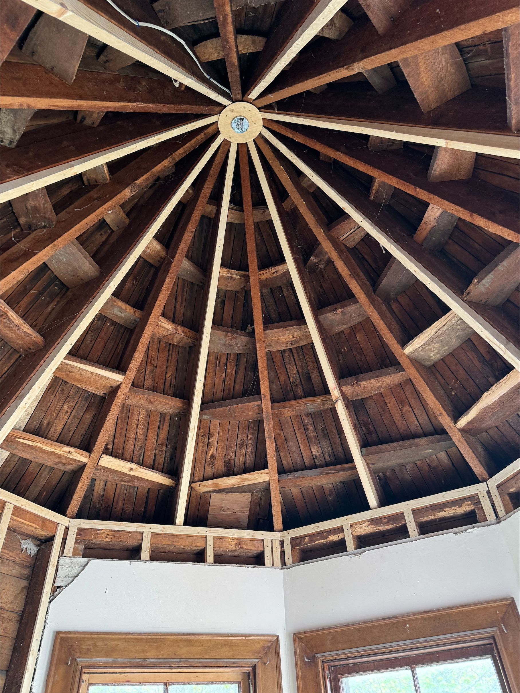 Wooden vaulted ceiling with exposed beams and a central skylight above white walls and windows