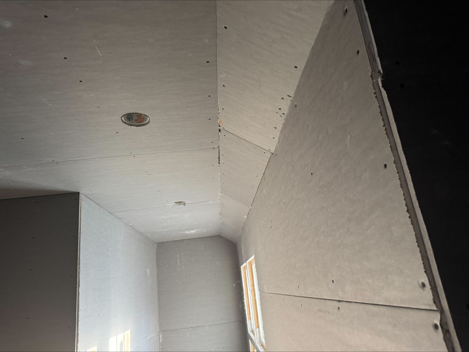 Gray unfinished interior with drywall ceiling, recessed light opening, and angled wall corner
