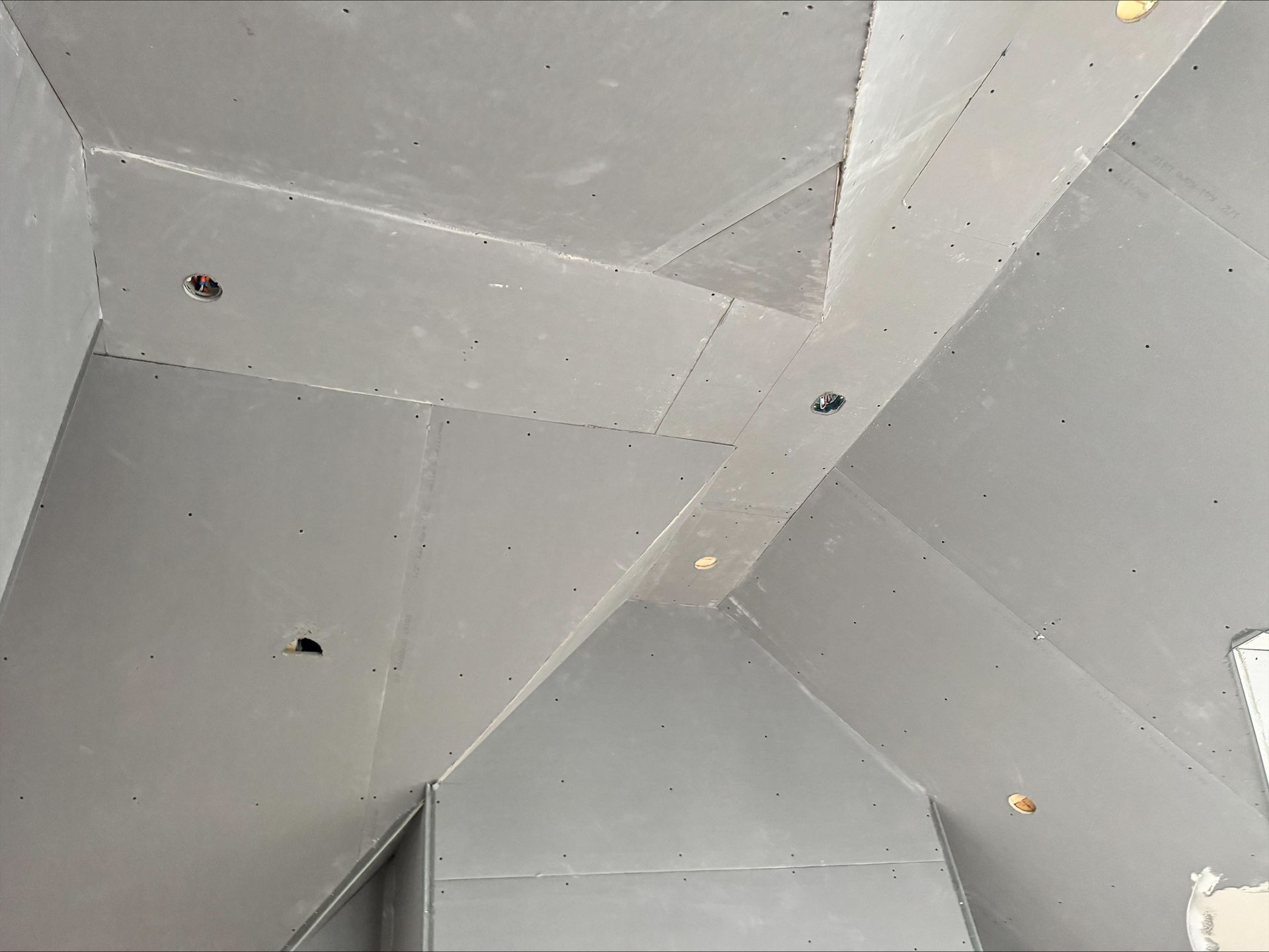 Gray geometric ceiling with angular panels and small recessed lights