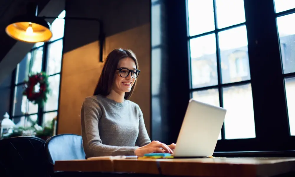 A woman is sitting at a table using a laptop computer.