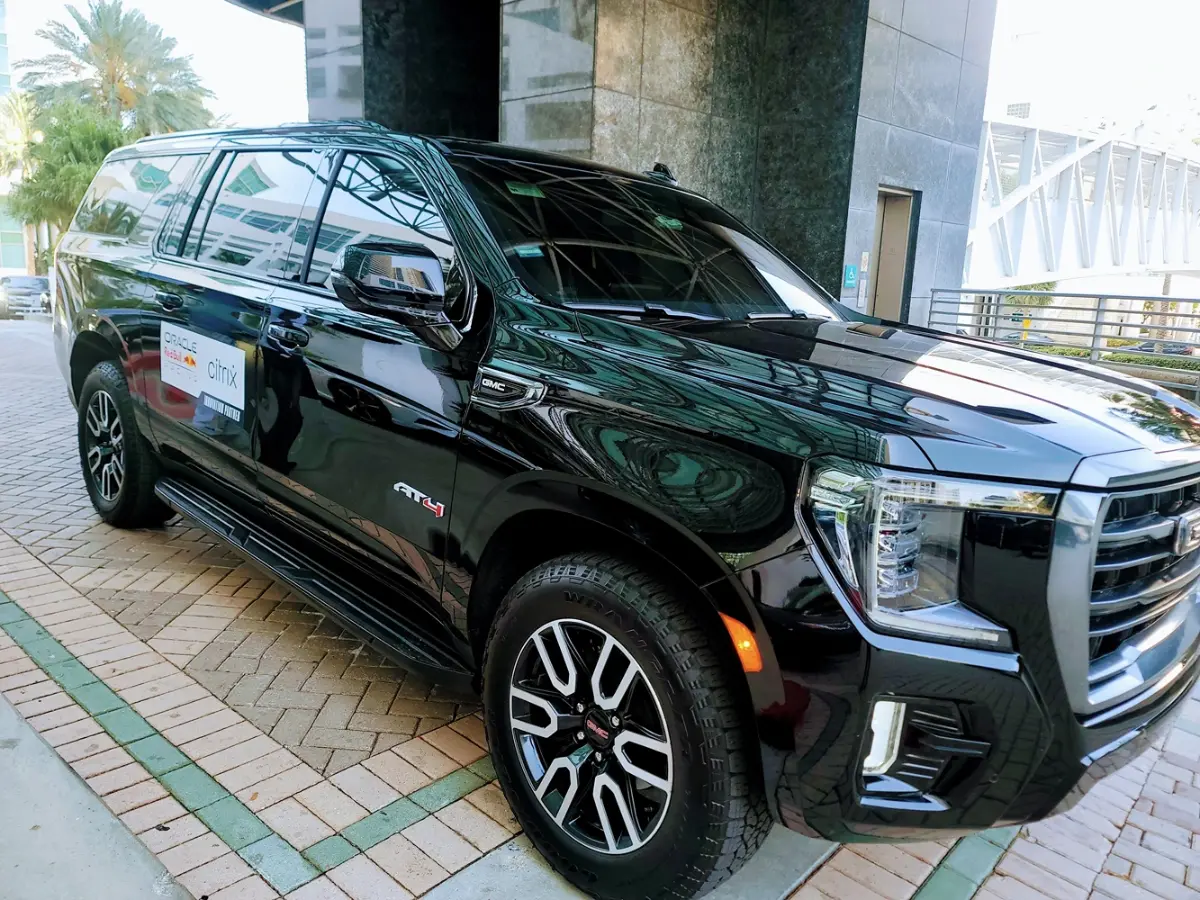 A black suv is parked on a brick sidewalk in front of a building.