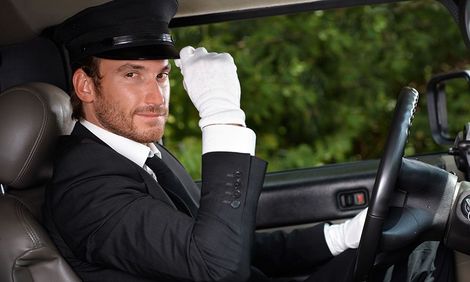 A man in a suit and tie is driving a car.