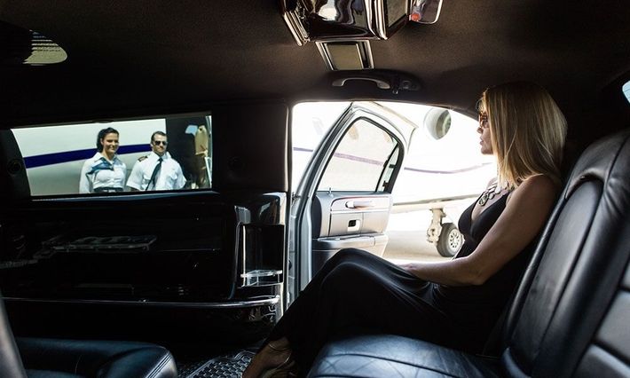 A woman is sitting in the back seat of a car watching a movie