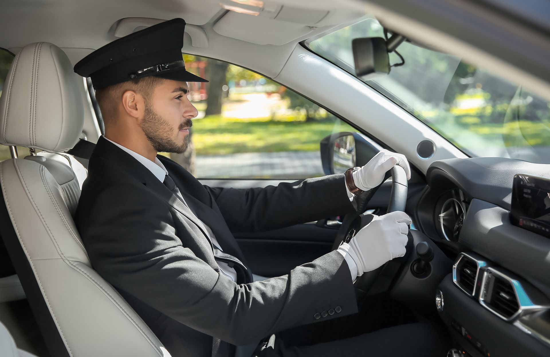 A man in a suit and hat is driving a car.