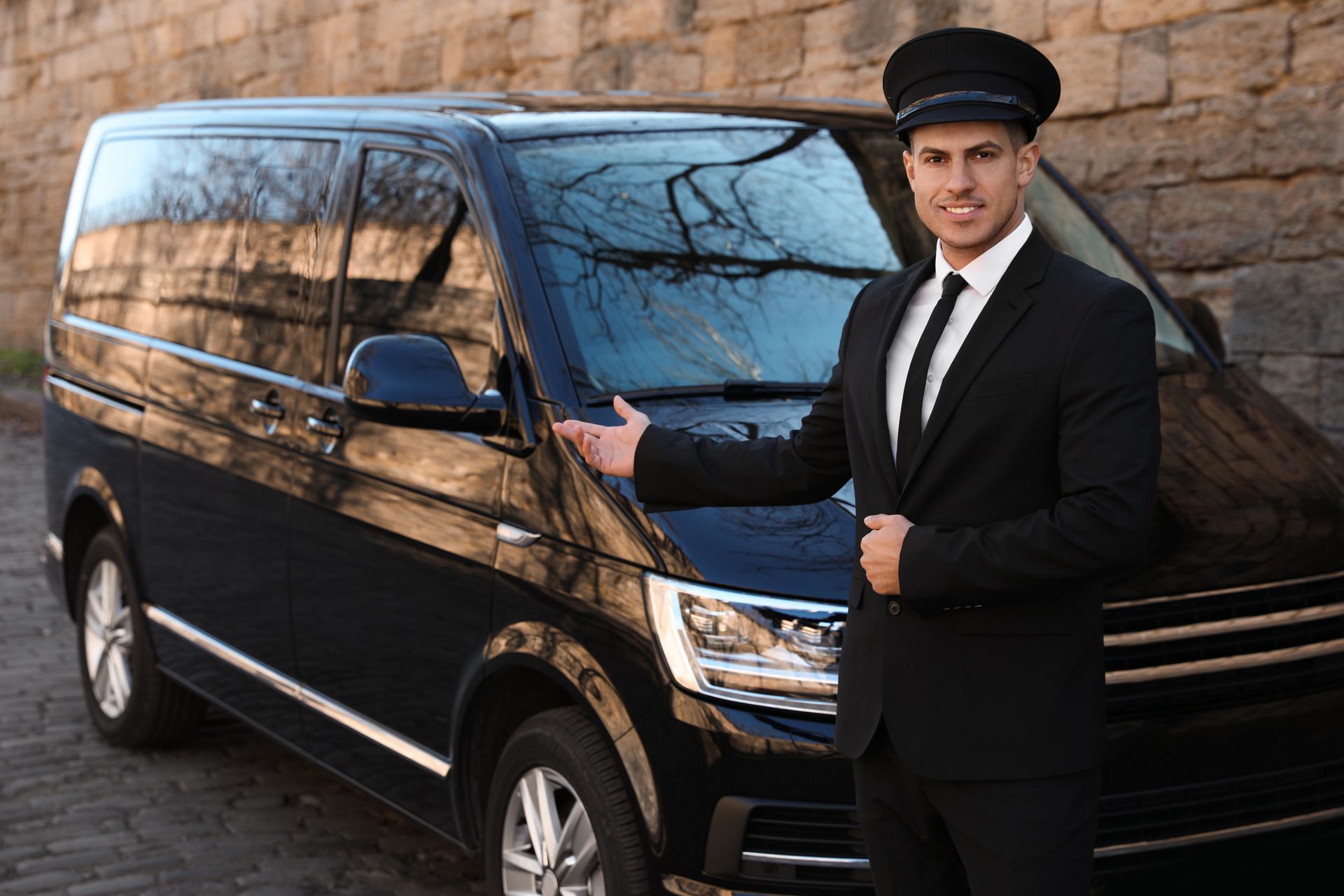A man in a suit and tie is standing next to a black van. A man in a suit and tie is standing next to a black van.
