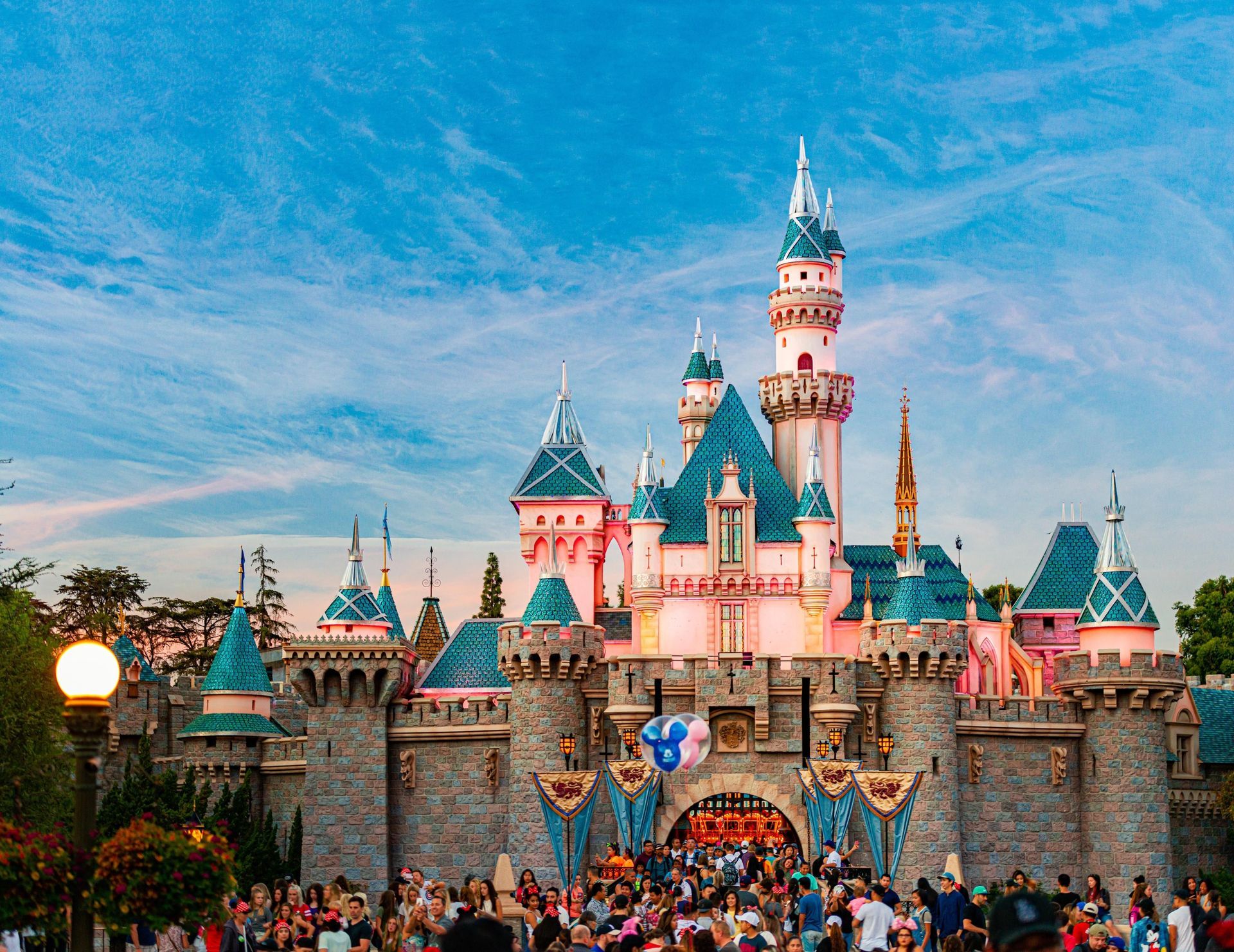 A crowd of people are gathered in front of the disney castle.